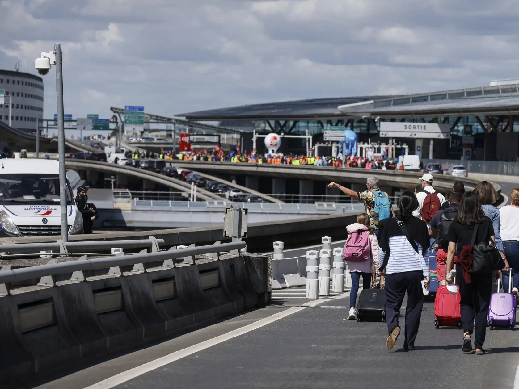 JB 22 Paríž - Cestujúci prichádzajú pešo na letisko Roissy - Charles de Gaulle, severne od Paríža 1. júla 2022 počas štrajku francúzskych odborárov na termináli (vľavo). Viaceré lety dnes zrušili pre štrajk francúzskych odborov na letisku v Paríži ako aj na ďalších francúzskych letiskách. Protestujúci odporári žiadajú zvýšenie platov v súvislosti so zrýchlením inflácie. FOTO TASR/AP

Travelers arrive on foot at Roissy-Charles de Gaulle airport while airport workers demonstrate, left, Friday, Jul