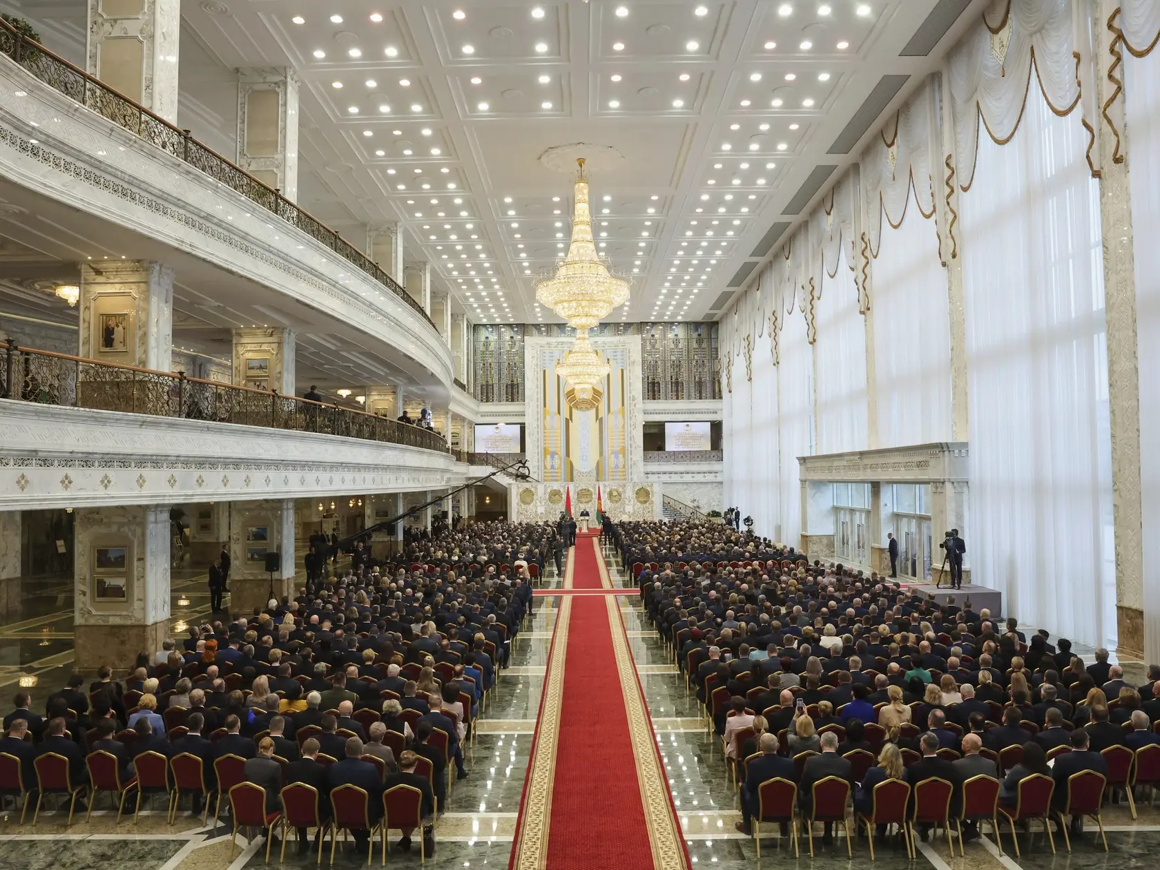 Na snímke ľudia sledujú, ako bieloruský prezident Alexandr Lukašenko skladá sľub počas jeho inaugurácie v Minsku 25. marca 2025.