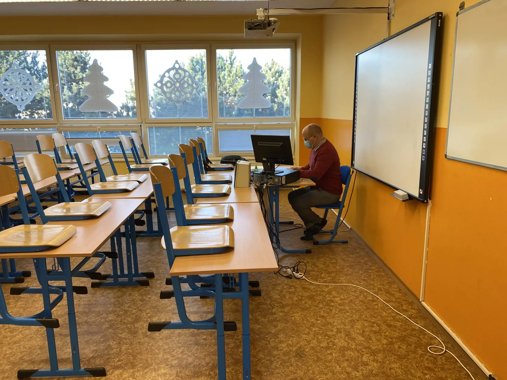 Učiteľ dejepisu počas dištančnej výučby v prázdnej triede.