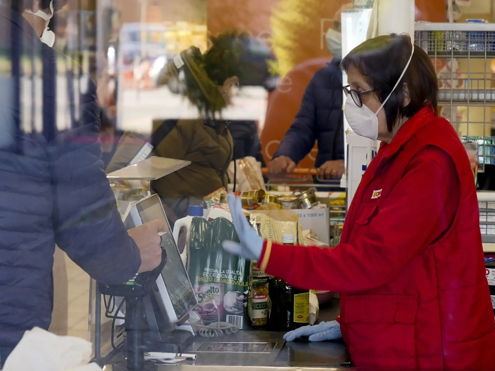 WA 38 Casalpusterlengo - Pokladníčka s ochranným rúškom na tvári sa rozpráva so zákazníkom v supermarkete v talianskom meste Casalpusterlengo na severe Talianska v pondelok 24. februára 2020. Talianska vláda v súvislosti so šírením koronavírusu nariadila dočasnú izoláciu desiatich miest a obcí v regióne Lombardsko (Codogno, Castiglione d'Adda, Casalpusterlengo, Fombio, Maleo, Somaglia, Bertonico, Terranova dei Passerini, Castelgerundo a San Fiorano) a mestečka Vo v regióne Benátsko. Izolácia sa 