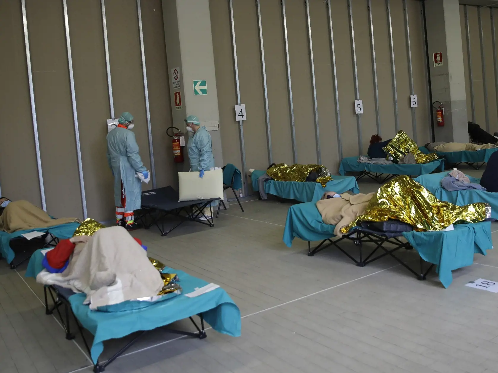 KK23 Brescia - Pacienti ležia na posteliach v jednom zo stanov pred nemocnicou v talianskom meste Brescia 12. marca 2020.  Už viac ako 1000 obetí na životoch si vyžiadala nákaza novým typom koronavírusu v Taliansku, informovala vo štvrtok agentúra AFP. Počet úmrtí v krajine dosiahol 1016 a nakazených je viac ako 15.000 ľudí. FOTO TASR/AP
Patients lie on beds at one of the emergency structures that were set up to ease procedures at the Brescia hospital, northern Italy, Thursday, March 12, 2020. I
