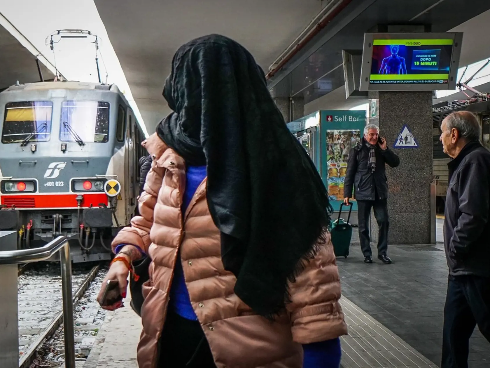 Žena na stanici v talianskom Neapole sa snaží pomocou šatky na hlave ochrániť pred hrozbu koronavírusu.
