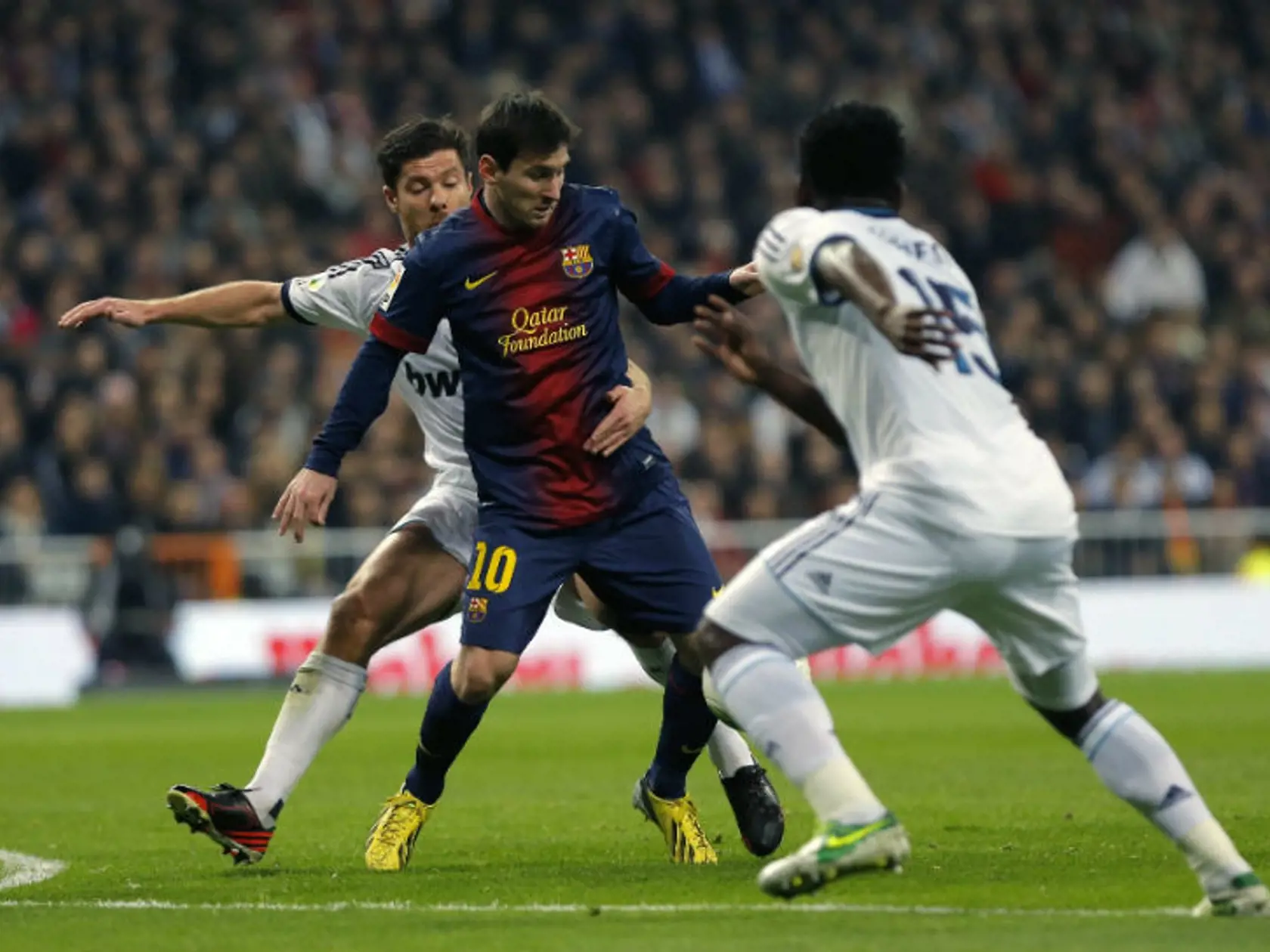 Hráč FC Barcelona Lionel Messi (druhý sprava) v súboji s hráčom Realu Madrid Xabim Alonsom (vľavo).