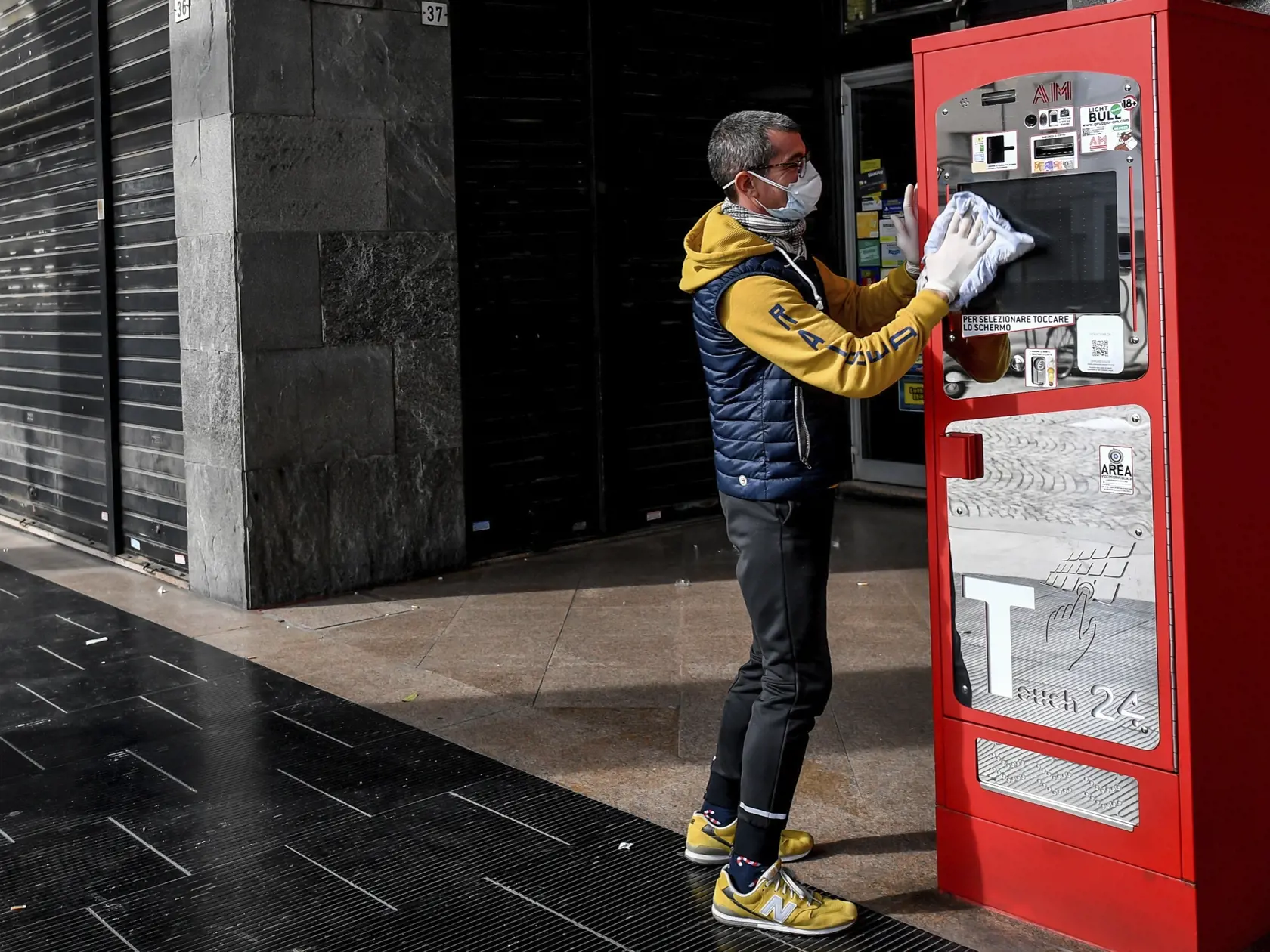 KK65 Casalpusterlengo - Na snímke muž v ochrannom rúšku čistí a dezinfikuje automat na cigarety v talianskom meste Casalpusterlengo 23. februára 2020.  Novým koronavírusom SARS-CoV-2 sa v Taliansku nakazilo už viac ako 100 ľudí. Oznámil to v nedeľu vo vysielaní spravodajskej televízie Sky TG24 guvernér regiónu Lombardsko Attilio Fontana.  Taliansko sa tak stalo najviac zasiahnutou krajinou v Európe. Najviac zo 132 infikovaných (89) hlásila práve z Lombardska. Prvé prípady boli zaznamenané aj v r