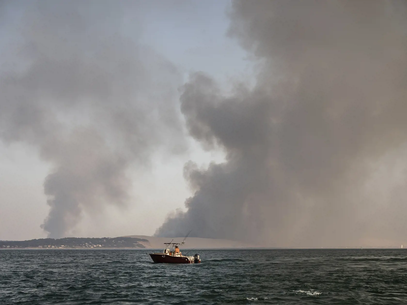 KK37 Pilat sur Mer - Dym stúpa nad plážou Pilat sur Mer v juhozápadnom Francúzsku z obrovského lesného požiaru, ktorý zachvátil tisícročný les  18. júla 2022.
