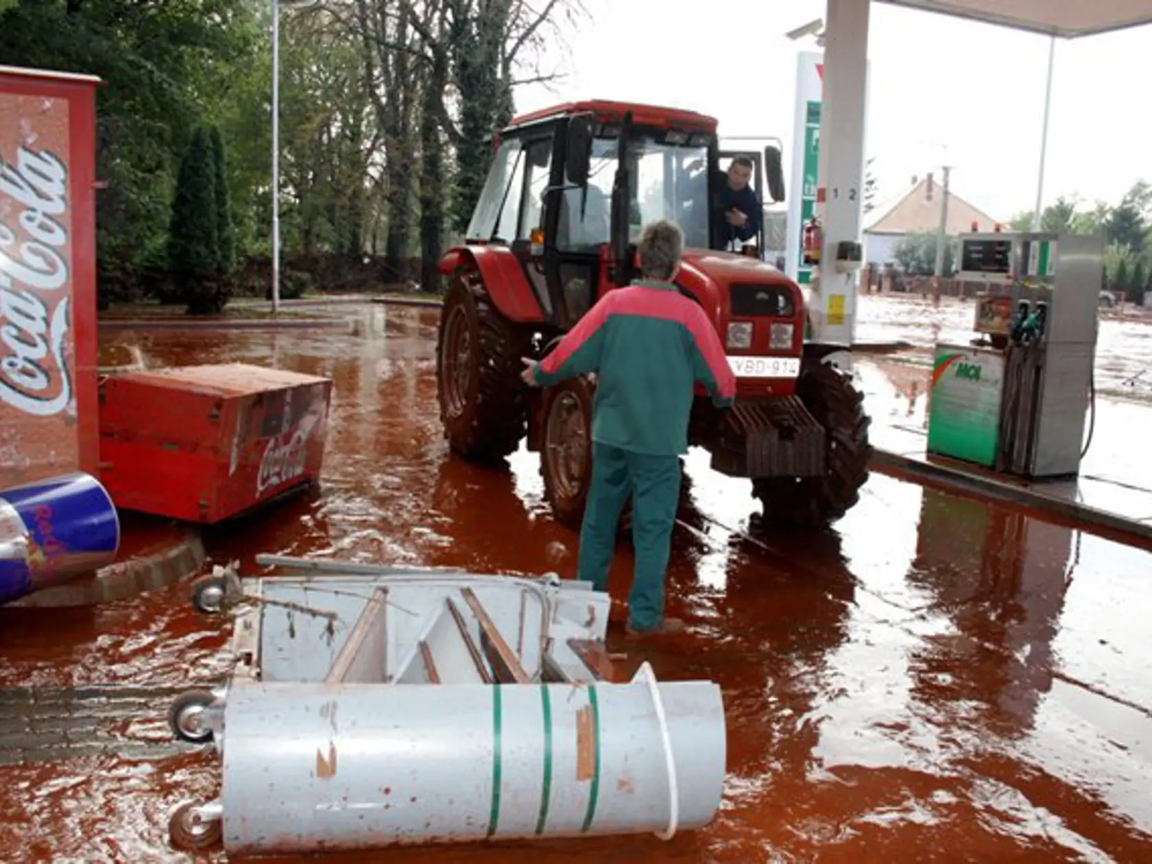 Zamestnanec pumpy prosí o pomoc záchranára prichádzajúceho na traktore v zaplavenom Devecséri, 164 km juhozápadne od Budapešti 4.októbra 2010. Pri pretrhnutí nádrže s toxickým kalom, patriacej hlinikárni, zomrel jeden človek, traja sú nezvestní a najmenej 60 ľudí utrpelo zranenia.