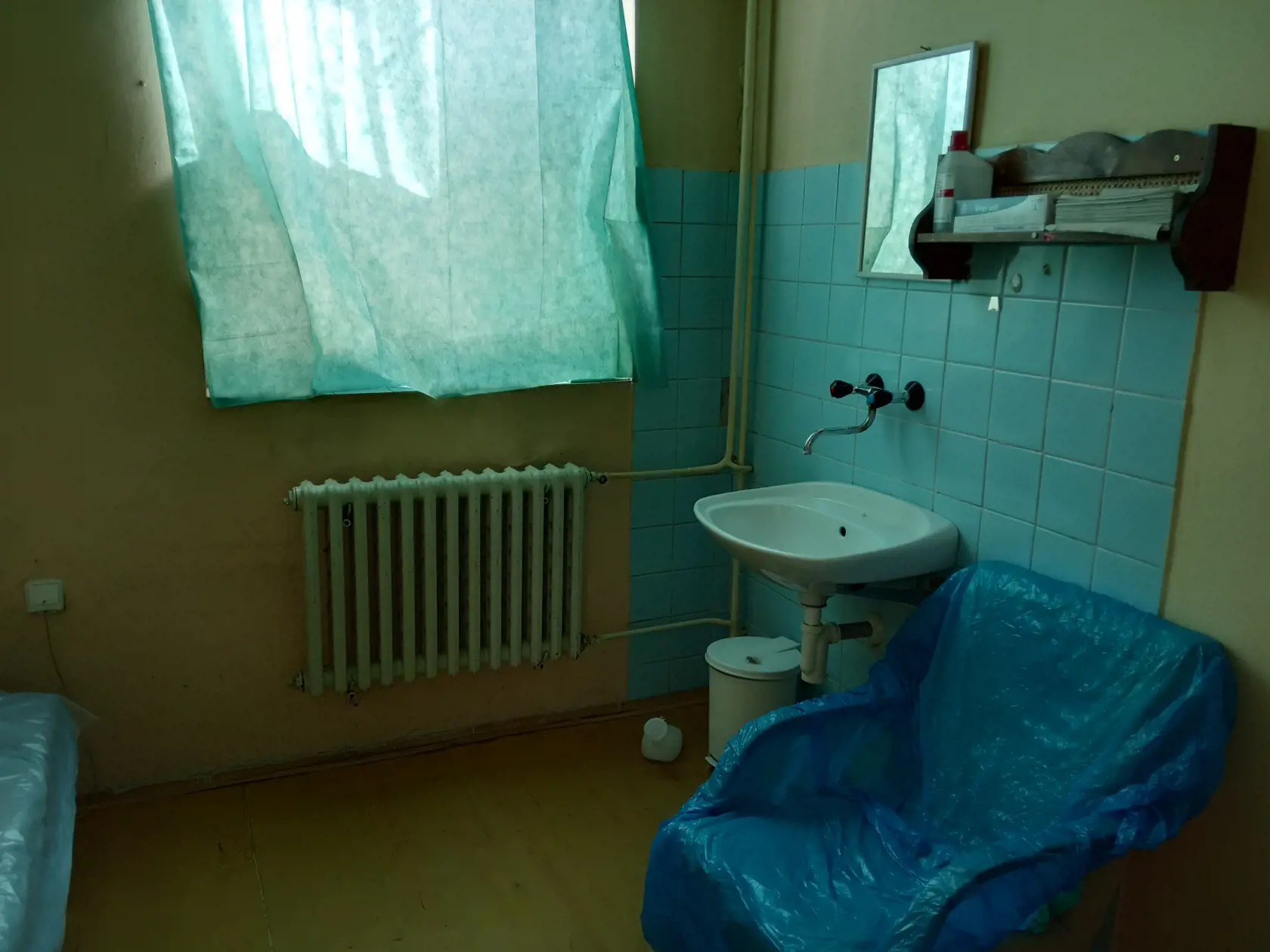 Staré kreslo pri umývadle pod ktorým je "bažant" na vykonávanie malej potreby.