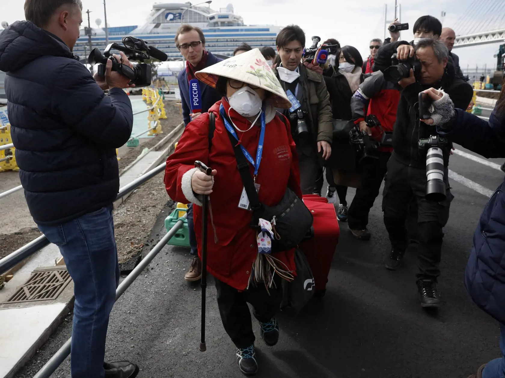 KK4 Jokohama - Na snímke cestujúca obklopená novinármi po odchode z výletnej lode Diamond Princess v Jokohame 19. februára 2020. Plavidlo s približne 3700 ľuďmi na palube kotví za karanténnych podmienok v japonskom prístave Jokohama od 3. februára, keď mužovi, ktorý sa vylodil v Hongkongu, diagnostikovali nový koronavírus. Na lodi sa infikovalo viac než 540 osôb; ide o najväčšiu koncentráciu nákazy mimo pevninskej Číny, kde epidémia vypukla. FOTO TASR/AP
An unidentified passenger is surrounded b