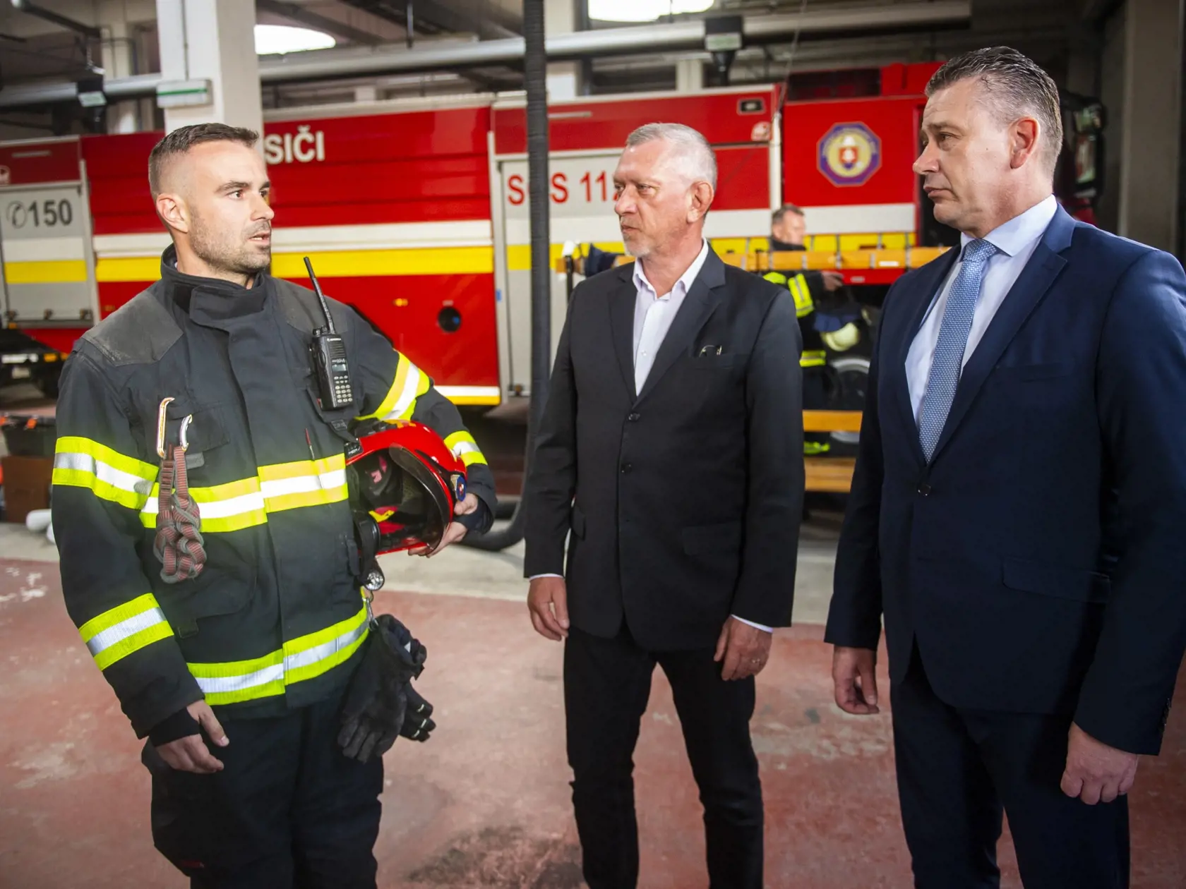 Na snímke zľava hasič Richard Rehák, štátny tajomník ministerstva vnútra SR Vendelín Leintner a minister vnútra SR Roman Mikulec počas návštevy hasičov na Hasičskej stanici v Petržalke 4. mája 2022 v Bratislave. FOTO TASR - Jakub Kotian