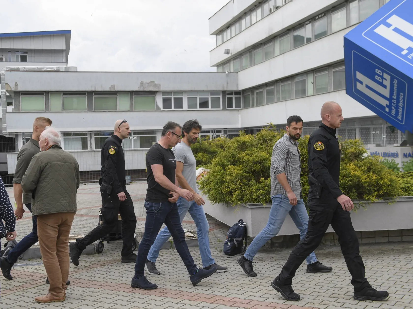 Na snímke podpredseda vlády SR a minister obrany Robert Kaliňák (tretí sprava, Smer-SD) a námestník Rooseveltovej nemocnice v Banskej Bystrici Milan Urbáni (štvrtý zľava) odchádzajú po brífingu, na ktorom informovali o aktuálnom zdravotnom stave premiéra Roberta Fica pred Rooseveltovou nemocnicou v Banskej Bystrici v nedeľu 19. mája 2024. Premiér Robert Fico (Smer-SD) je momentálne mimo ohrozenia života. Jeho stav je naďalej vážny.  Vicepremiér doplnil, že prevoz predsedu vlády do inej nemocnice