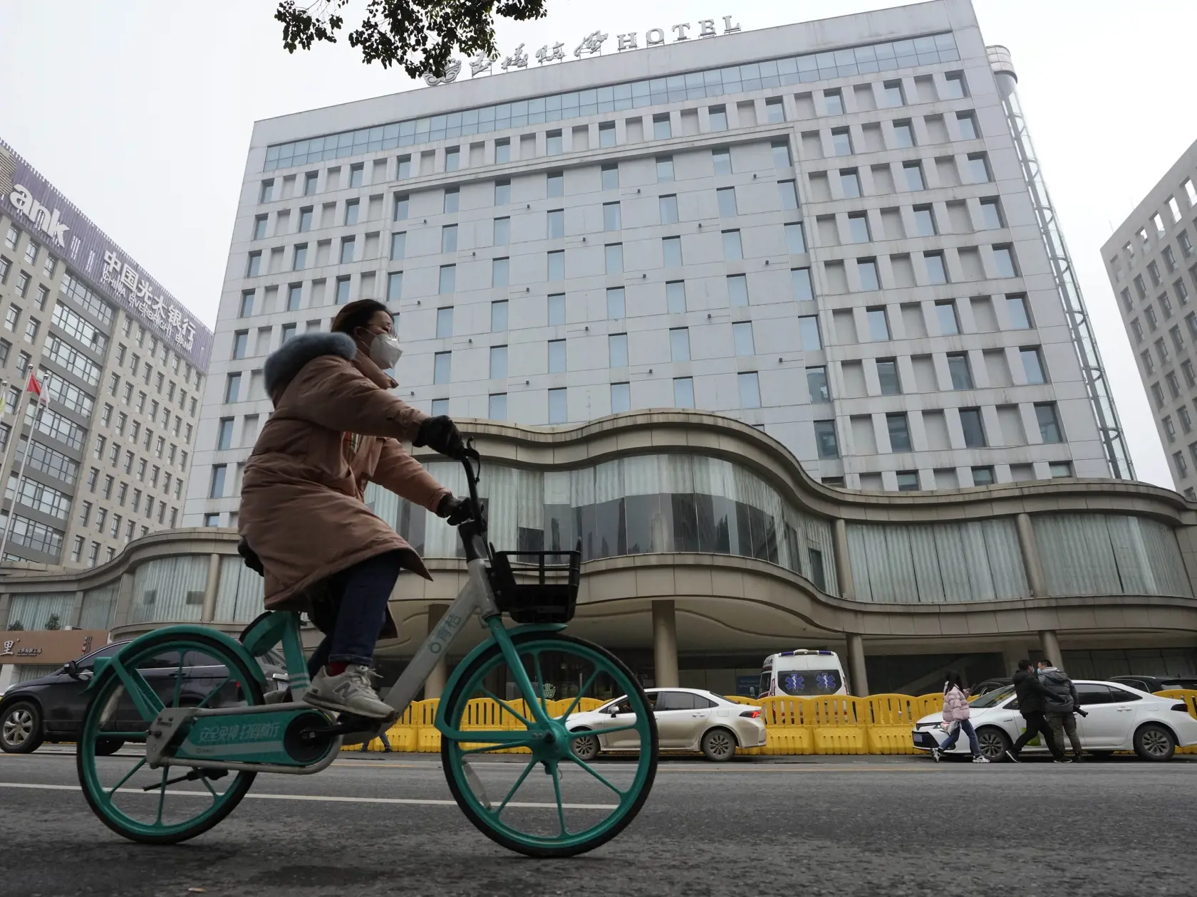 WA 23 Wu-chan - Žena na bicykli prechádza okolo hotela, v ktorom skupina odborníkov Svetovej zdravotníckej organizácie (WHO) ukončila  dvojtýždňovú karanténu v čínskom meste Wu-chan vo štvrtok 28. januára 2021. Úlohou tímu je v spolupráci s čínskymi vedcami zistiť, či sa dá spätne vystopovať pôvod nového typu koronavírusu. Koronavírus, ktorý spôsobuje chorobu COVID-19, najprv zistili pred vyše rokom v spomínanom stredočínskom meste Wu-chan. Pátranie po pôvode koronavírusu je politicky citlivá zá