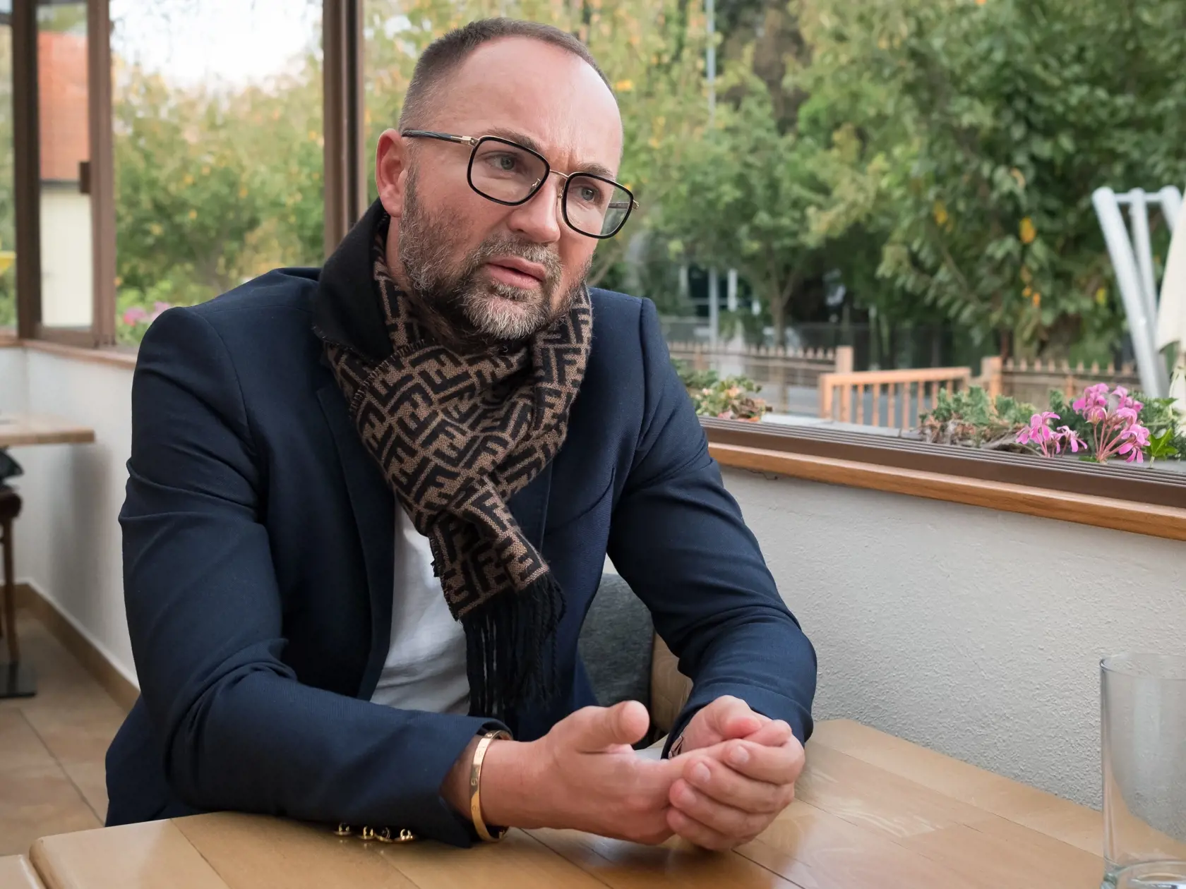 Svetlana El Halawany: Sako nadčasového námorníckeho typu je ozaj výborná voľba. Elegantný odtieň, kvalitný materiál i gombíky sú zárukou luxusného looku. Páči sa mi aj voľba simple bieleho nátelníka .
Na krku dominuje šáll z módneho domu Fendi, v príznačnom printe zucca. Zápästie zdobí luxusná klasika Cartier love bracelet, opäť tón v tóne s gombíkmi. V princípe nie je tento outfit rušivý, za predpokladu, že zrejme k šálu bol niekde zavesený aj chic kabát. Rám kvalitných okuliarov celkovo opäť korešponduje s tvárou a lookom. Oceňujem aj upravené, čisté, krátke nechty .