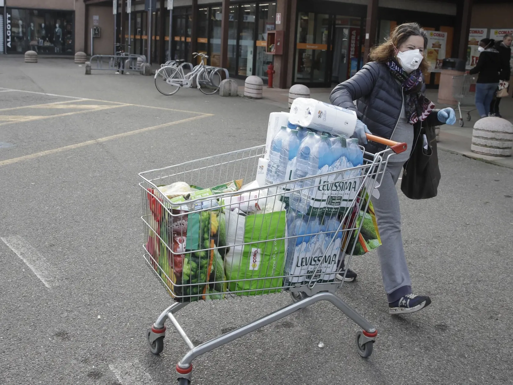 KK40 Codogno - Na snímke žena s ochranným rúškom na tvári tlačí nákupný košík pred supermarketom v talianskom meste Codogno 23. februára 2020.  Novým koronavírusom SARS-CoV-2 sa v Taliansku nakazilo už viac ako 100 ľudí. Oznámil to v nedeľu vo vysielaní spravodajskej televízie Sky TG24 guvernér regiónu Lombardsko Attilio Fontana.  Taliansko sa tak stalo najviac zasiahnutou krajinou v Európe. Najviac zo 132 infikovaných (89) hlásila práve z Lombardska. Prvé prípady boli zaznamenané aj v regiónoch