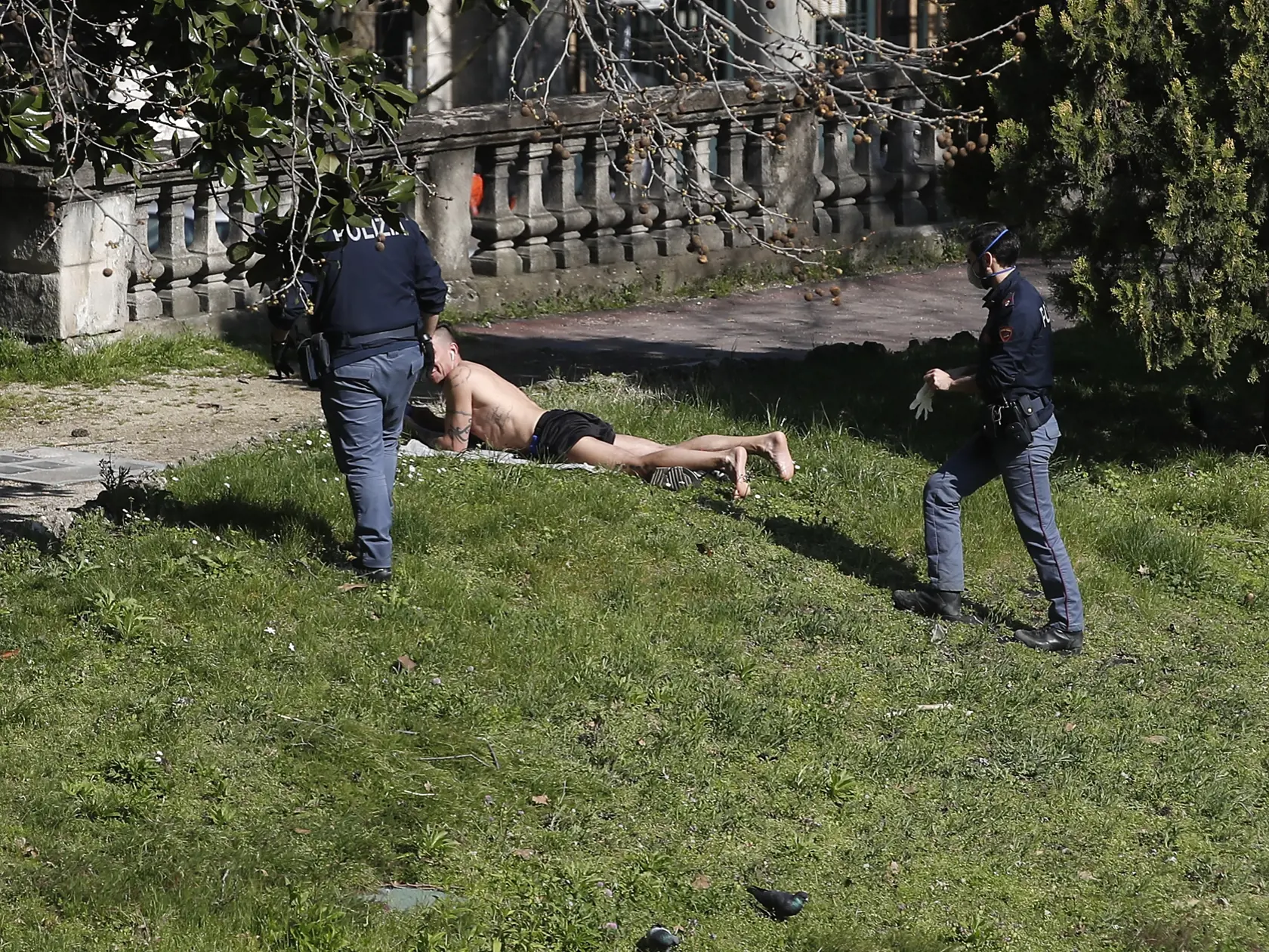 WA 9 Miláno - Policajti žiadajú muža, ktorý sa opaľuje, aby opustil park v Miláne vo štvrtok 19. marca 2020. V rámci vládnych nariadení v súvislisti s pandémiou choroby COVID-19 majú obyvatelia Talianska výrazne obmedzený pohyb mimo svojich domovov, ktoré môžu opustiť len na nákup potravín, liekov a drogistického tovaru a na presuny do zamestnania. Školy všetkých typov sú tiež zavreté. Taliansko je najhoršie postihnutou európskou krajinou, pokiaľ ide o koronavírusovú pandémiu. FOTO TASR/AP
  
It