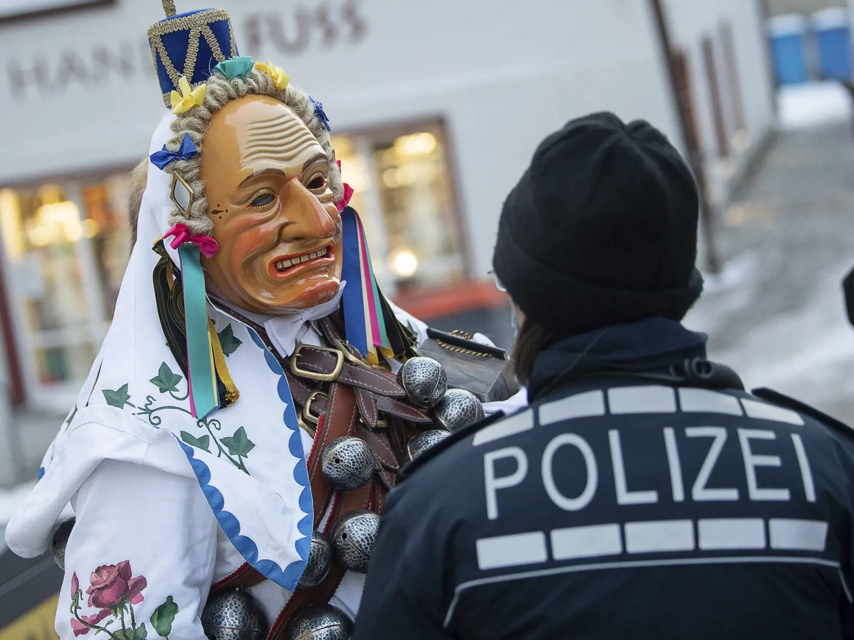 Na snímke osoba v kostýme a maske miestneho šaša (Federahannes), tradičnej postavy fašiangových sprievodov, diskutuje s policajtom v juhonemeckom meste Rottweil 15. februára 2021. Kvôli pandémii nového koronavírusu  bol fašiangový karneval v meste oficiálne zrušený, ale niektorí nadšenci si udalosť nenechali ujsť. FOTO TASR/AP