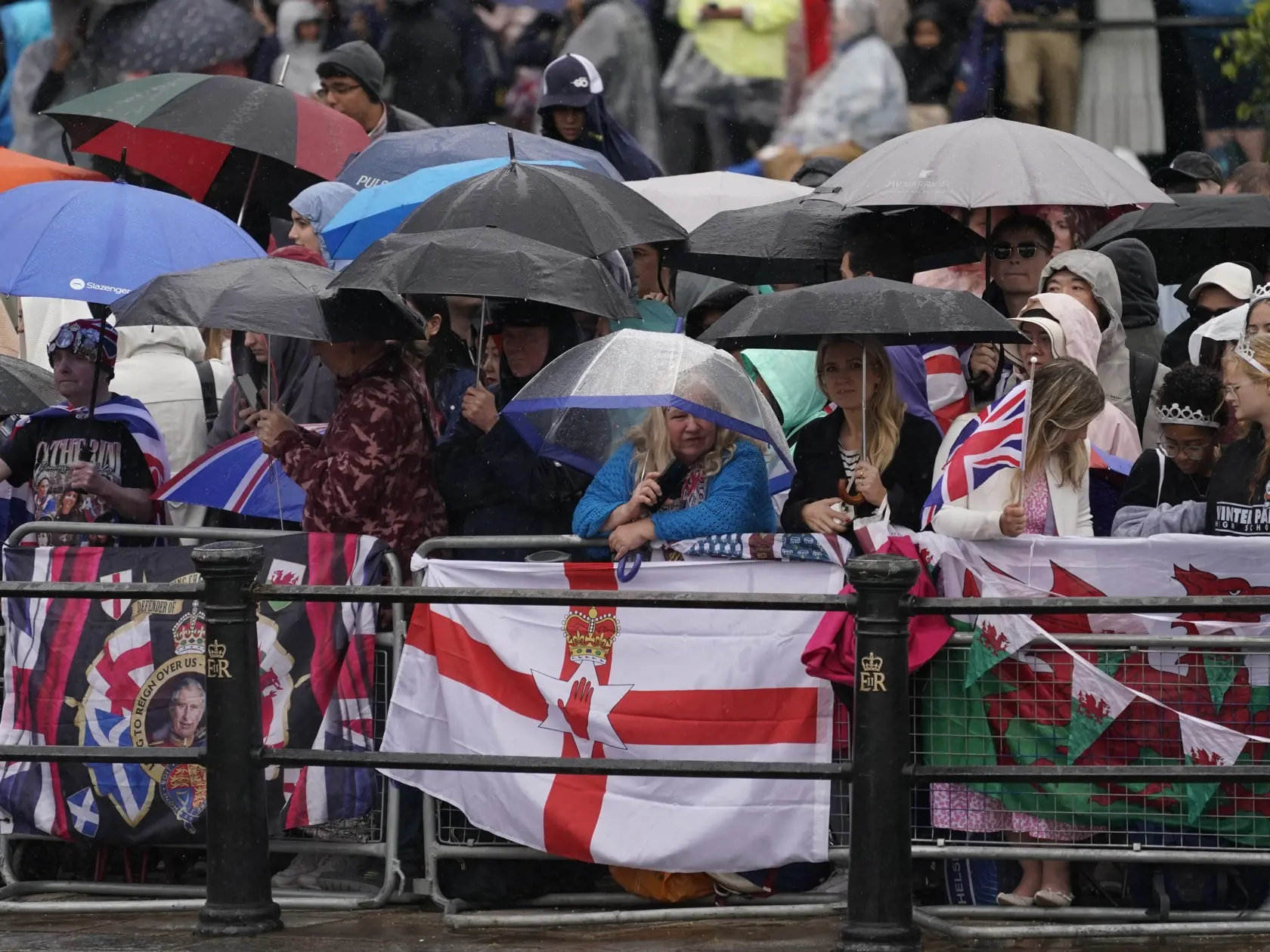 Ľudia držia dáždniky počas dažďa pred začiatkom vojenskej prehliadky Trooping the Colour na počesť narodenín britského kráľa Karola III. v centre Londýna v sobotu 15. júna 2024. Koná sa tradične v júni, narodeniny má Karol III. až 14. novembra.  Britská princezná Catherine sa zúčastní na slávnostnej vojenskej prehliadke Trooping the Colour. Pôjde o jej prvé verejné vystúpenie od začiatku roka, informuje TASR podľa správy agentúry AP. FOTO TASR/AP