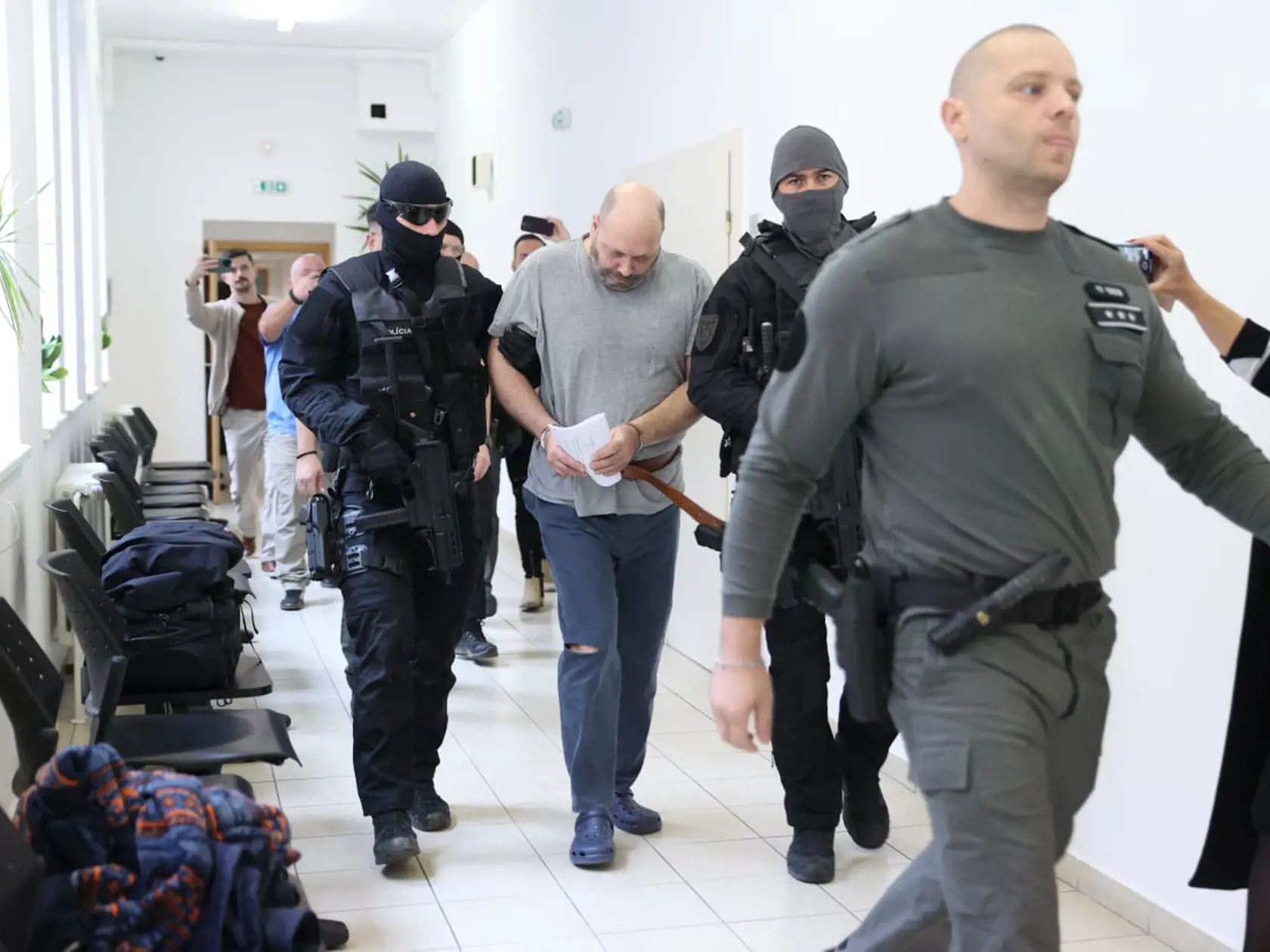 Tomáša (44), obvineného z vraždy svojich rodičov, privádzajú kukláči priviedli na súd 18. októbra 2024.