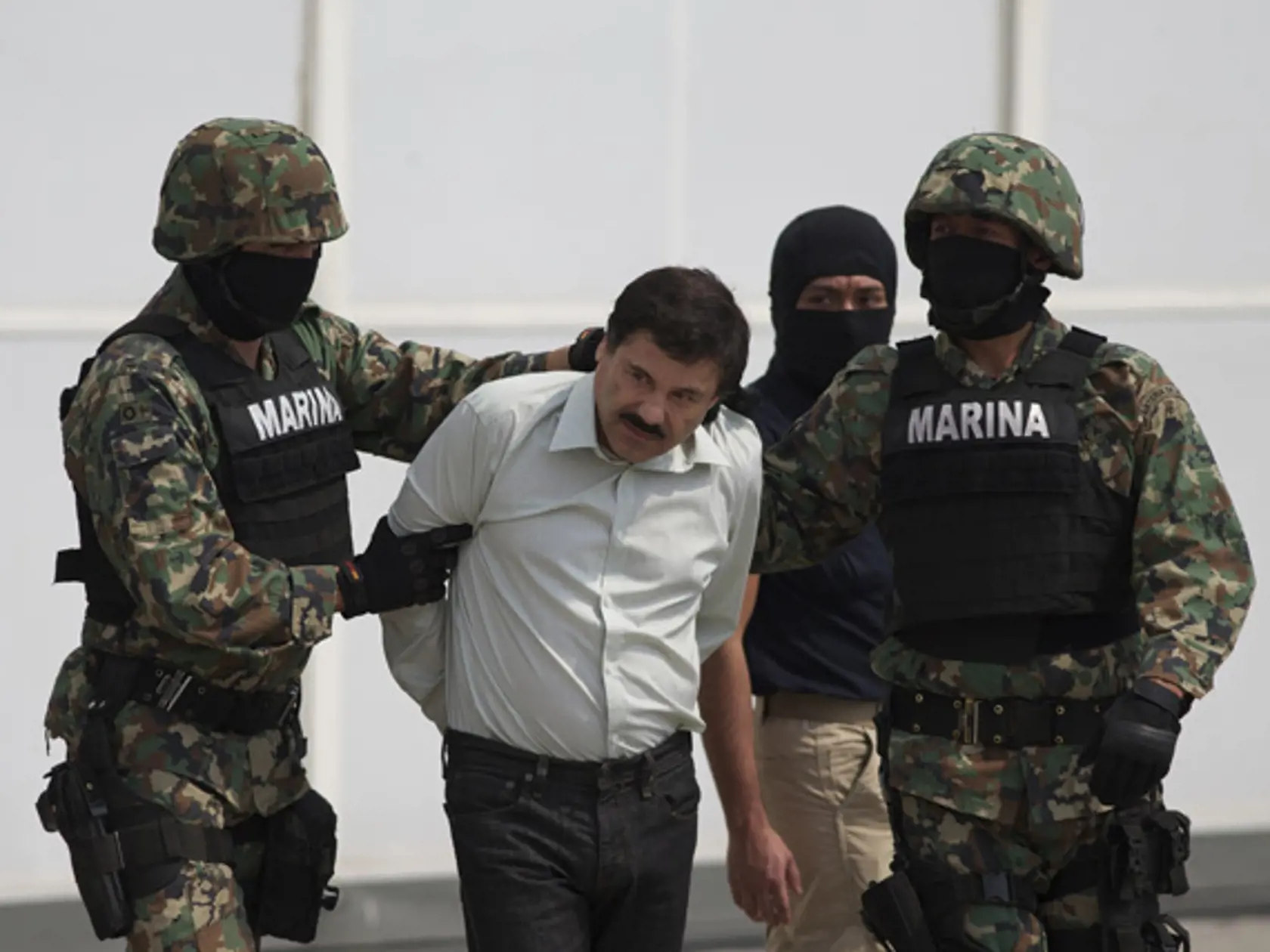 Joaquin "El Chapo" Guzman is escorted to a helicopter in handcuffs by Mexican navy marines at a navy hanger in Mexico City, Mexico, Saturday, Feb. 22, 2014. A senior U.S. law enforcement official said Saturday, that Guzman, the head of Mexicoís Sinaloa Cartel, was captured alive overnight in the beach resort town of Mazatlan. Guzman faces multiple federal drug trafficking indictments in the U.S. and is on the Drug Enforcement Administrationís most-wanted list.  (AP Photo/Eduardo Verdugo)