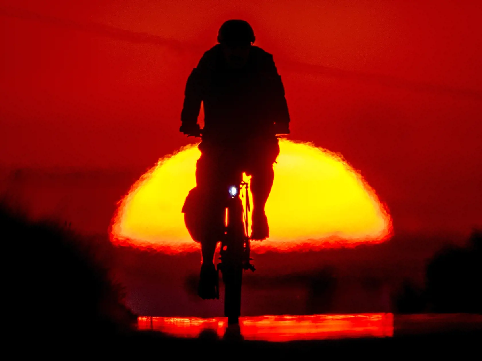 Toto leto trápilo všetko a všetkých silné nemilosrdné Slnko.  Na snímke muž ide na bicykli po malej ceste pri východe slnka na okraji nemeckého Frankfurtu nad Mohanom 4. júla 2022.