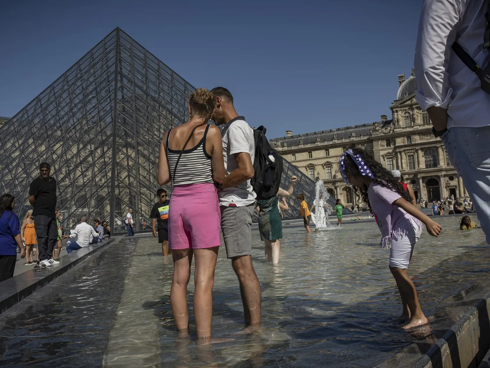 Ľudia sa osviežujú vo fontánach pred múzeom Louvre v Paríži 11. augusta 2022.