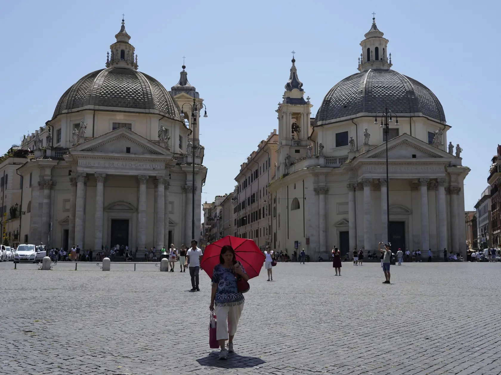 Žena sa skrýva pred slnkom počas horúceho dňa na námestí  Piazza del Popolo v centre Ríma 6. júla 2023.