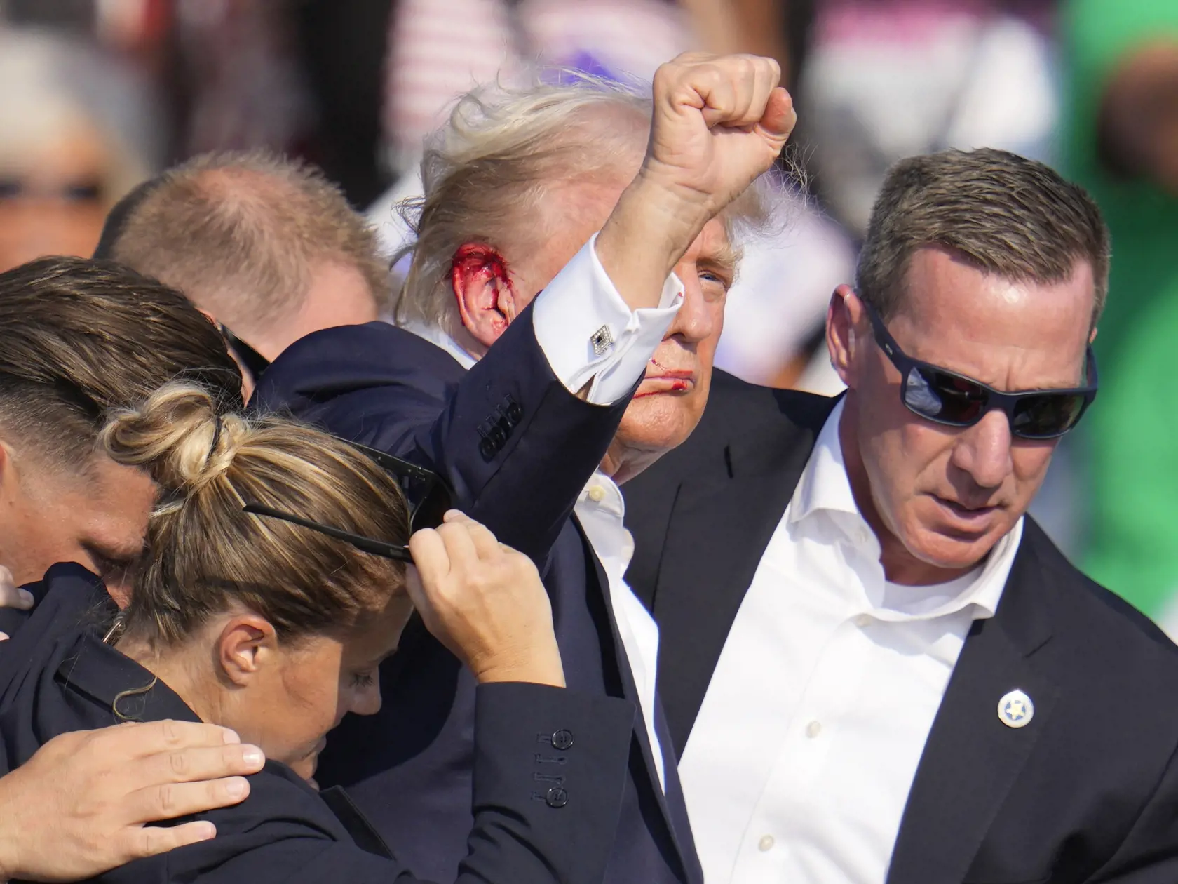 Republikánsky prezidentský kandidát Donald Trump (druhý sprava) máva pri odchode z pódia za pomoci ochrankárov z predvolebného mítingu v meste Butler v americkom štáte Pensylvánia 13. júla 2024. Trump potvrdil, že v sobotu na mítingu v Pensylvánii ho zasiahla guľka. Tá mu prestrelila hornú časť pravého ucha. Bývalý americký prezident sa vyjadril na sociálnej sieti, informuje TASR.