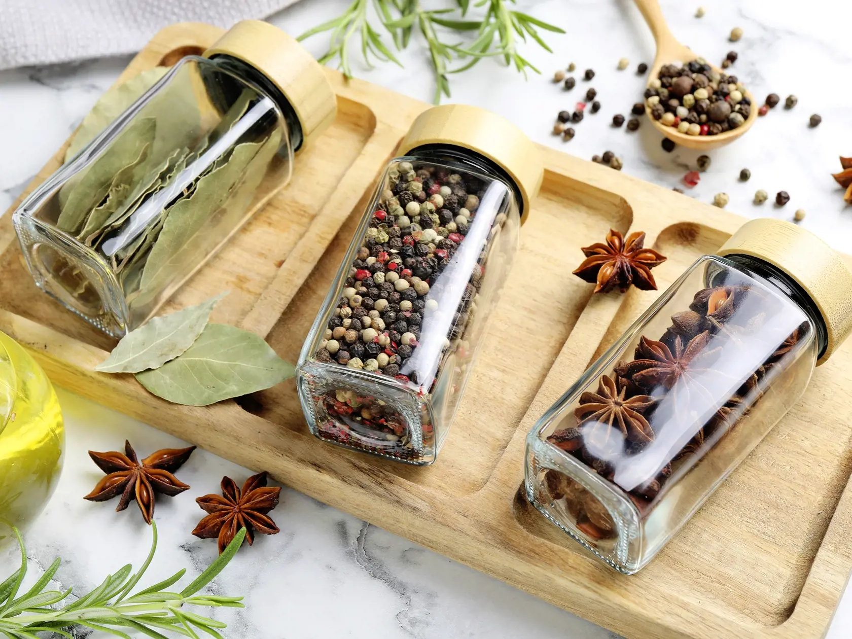 Glass jars with different spices on white marble table