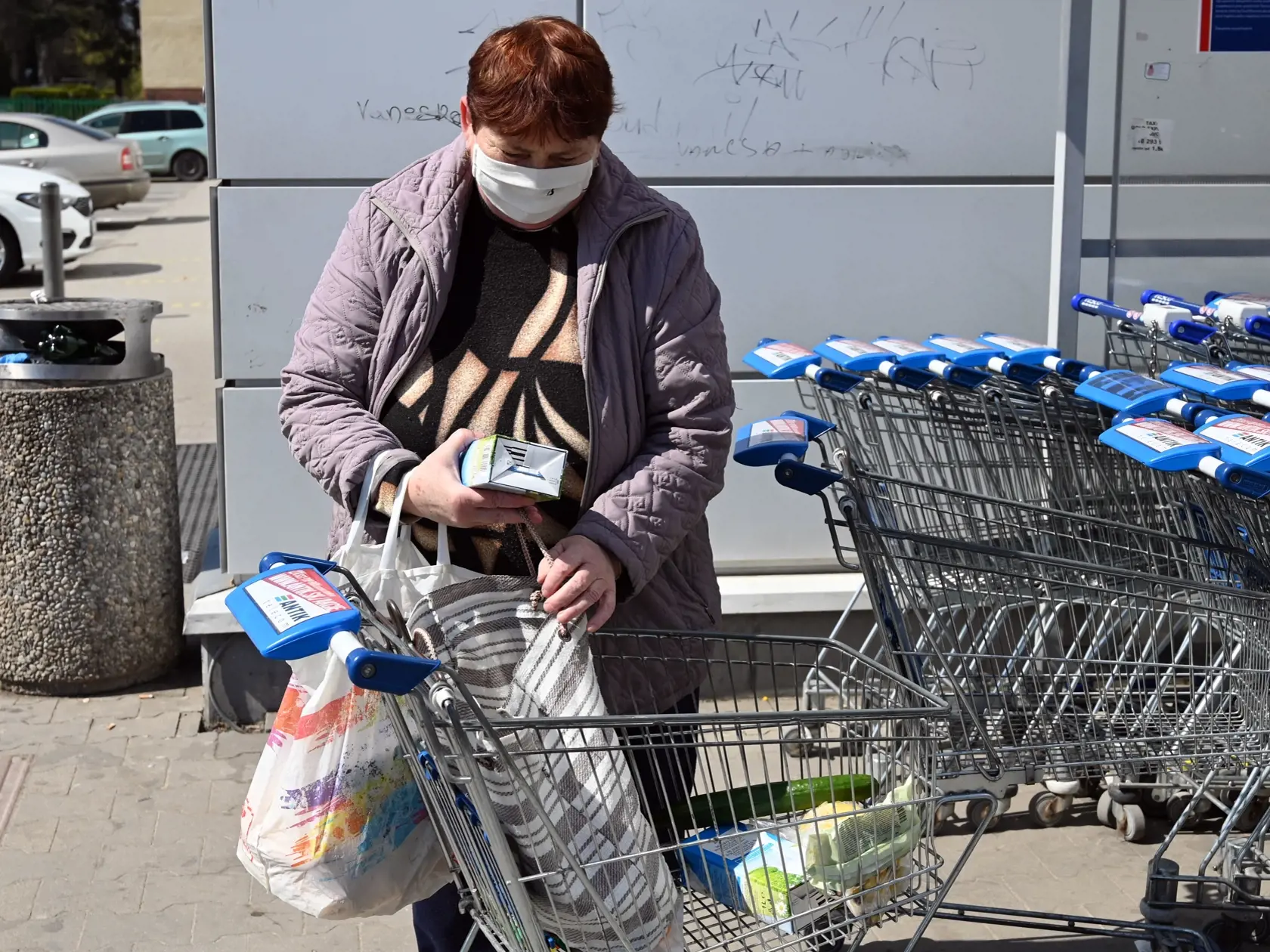 Na snímke seniorka si berie tašky z nákupného košíka.