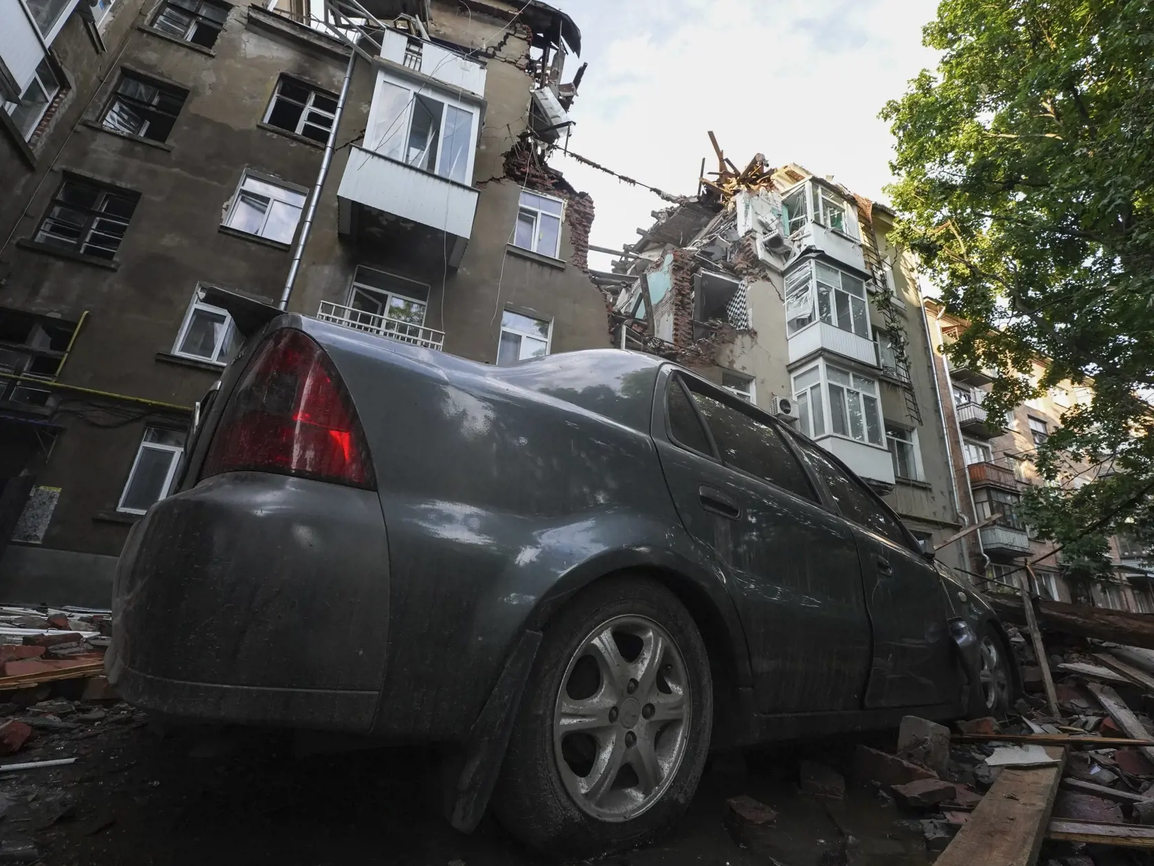 KK52 Sumy - Na snímke zničené auto a obytný dom po ruskom útoku na obytnú štvrť v ukrajinskom meste Sumy 3. júla 2023. FOTO TASR/AP
Damages of a car and an apartment building are seen after Russian attack at a residential area in Sumy, Ukraine, Monday, July 3, 2023. (AP Photo/Andrii Marienko)