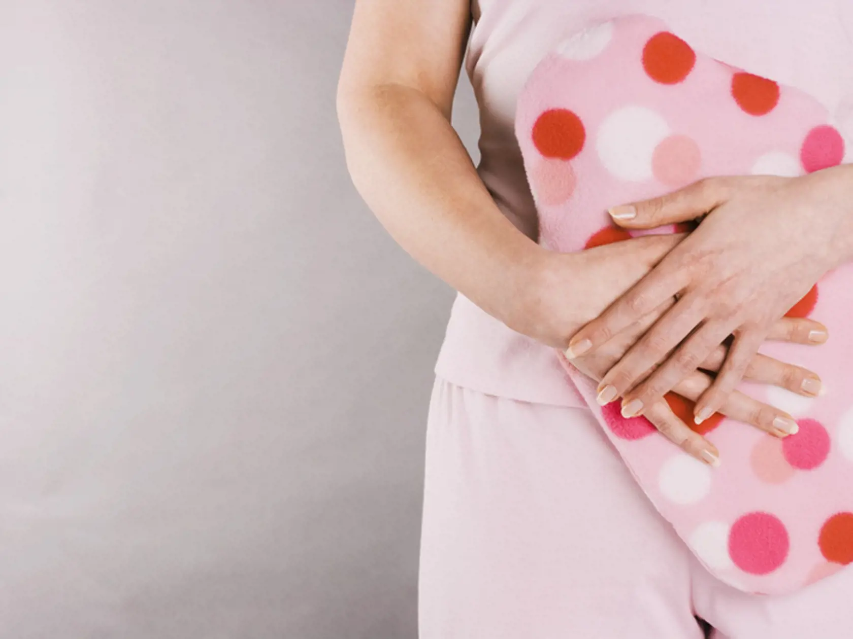 Woman holding hot water bottle over stomach