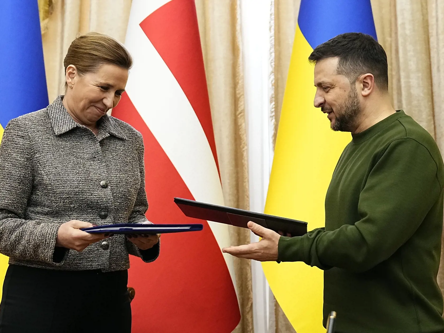 Dánska premiérka Mette Frederiksenová (vľavo) a ukrajinský prezident Volodymyr Zelenskyj sa usmievajú počas podpisu bezpečnostnej dohody s platnosťou na desať rokov v ukrajinskom meste Ľvov v piatok 23. februára 2024.