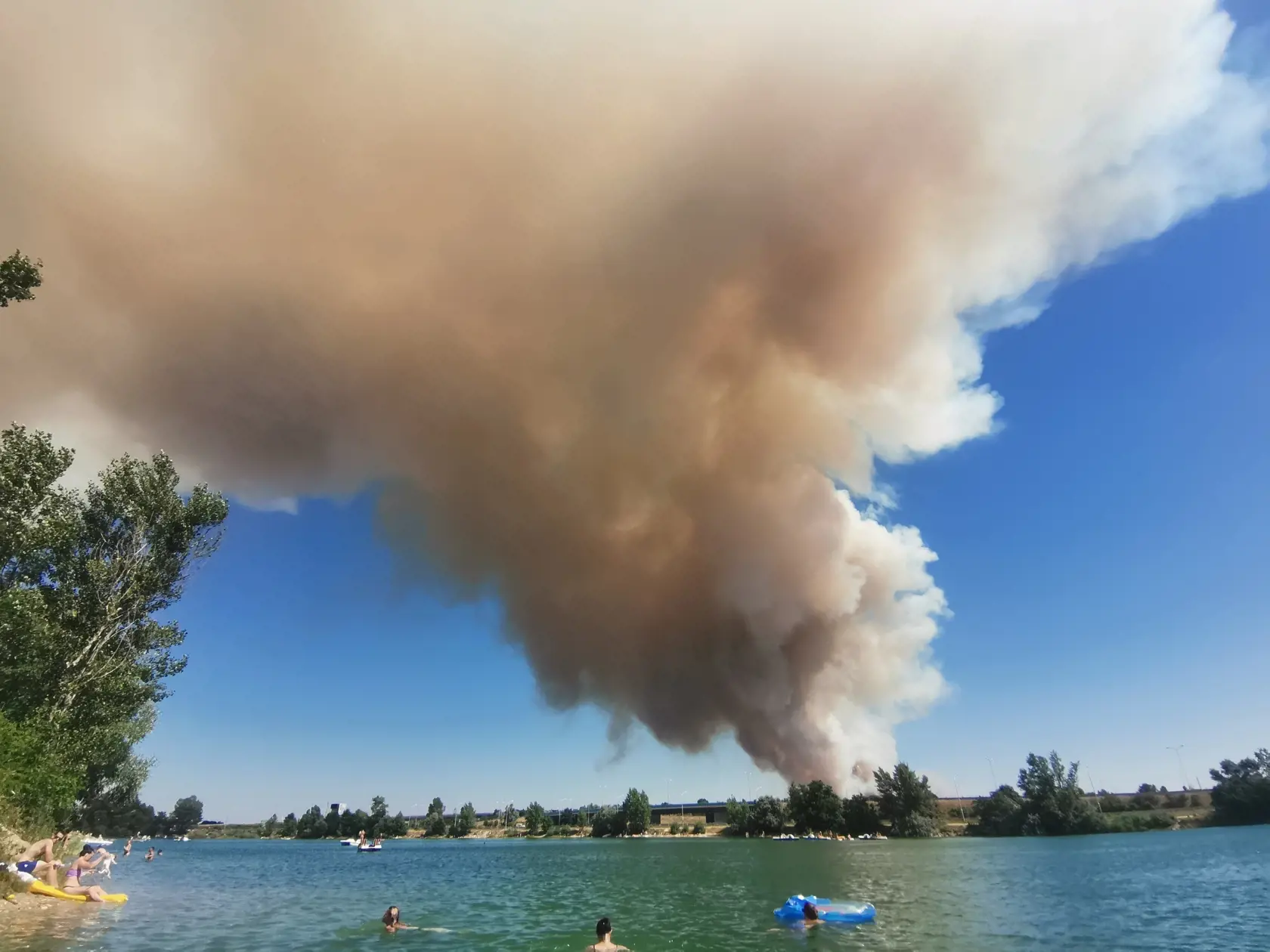 Na snímke požiar poľa v blízkosti bratislavského letiska v Moste pri Bratislave 15. júla 2023 viditeľný z jazera Bager vo Vajnoroch. FOTO TASR - Jakub Popelka