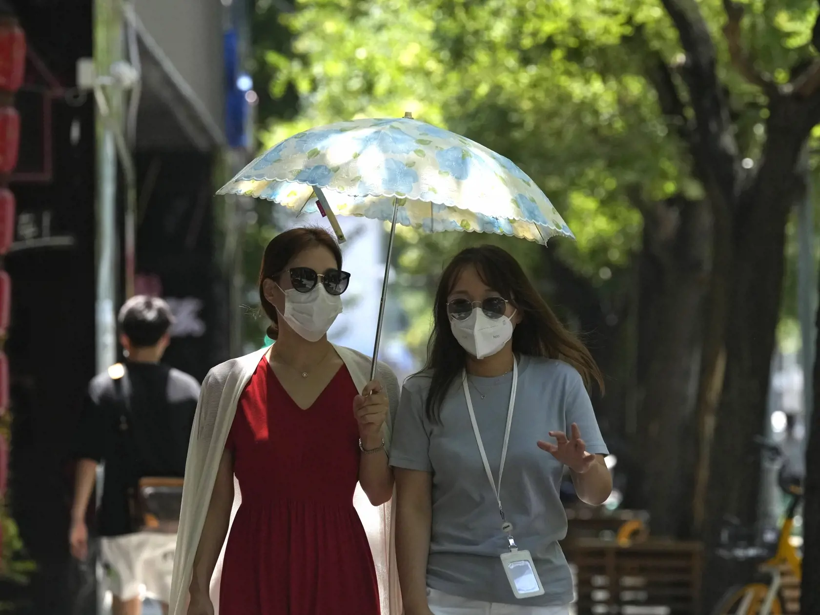 PK 10 Peking - Ženy s ochrannými rúškami a so slnečnými okuliarmi kráčajú ulicami Pekingu 13. júla 2022. FOTO TASR/AP

Residents wearing masks walk through a street with trees, Wednesday, July 13, 2022, in Beijing. (AP Photo/Ng Han Guan)