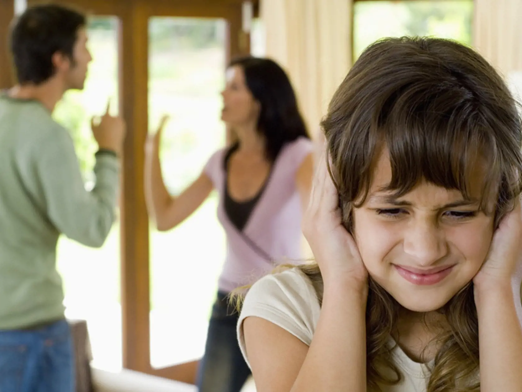 Girl covering ears while parents fight