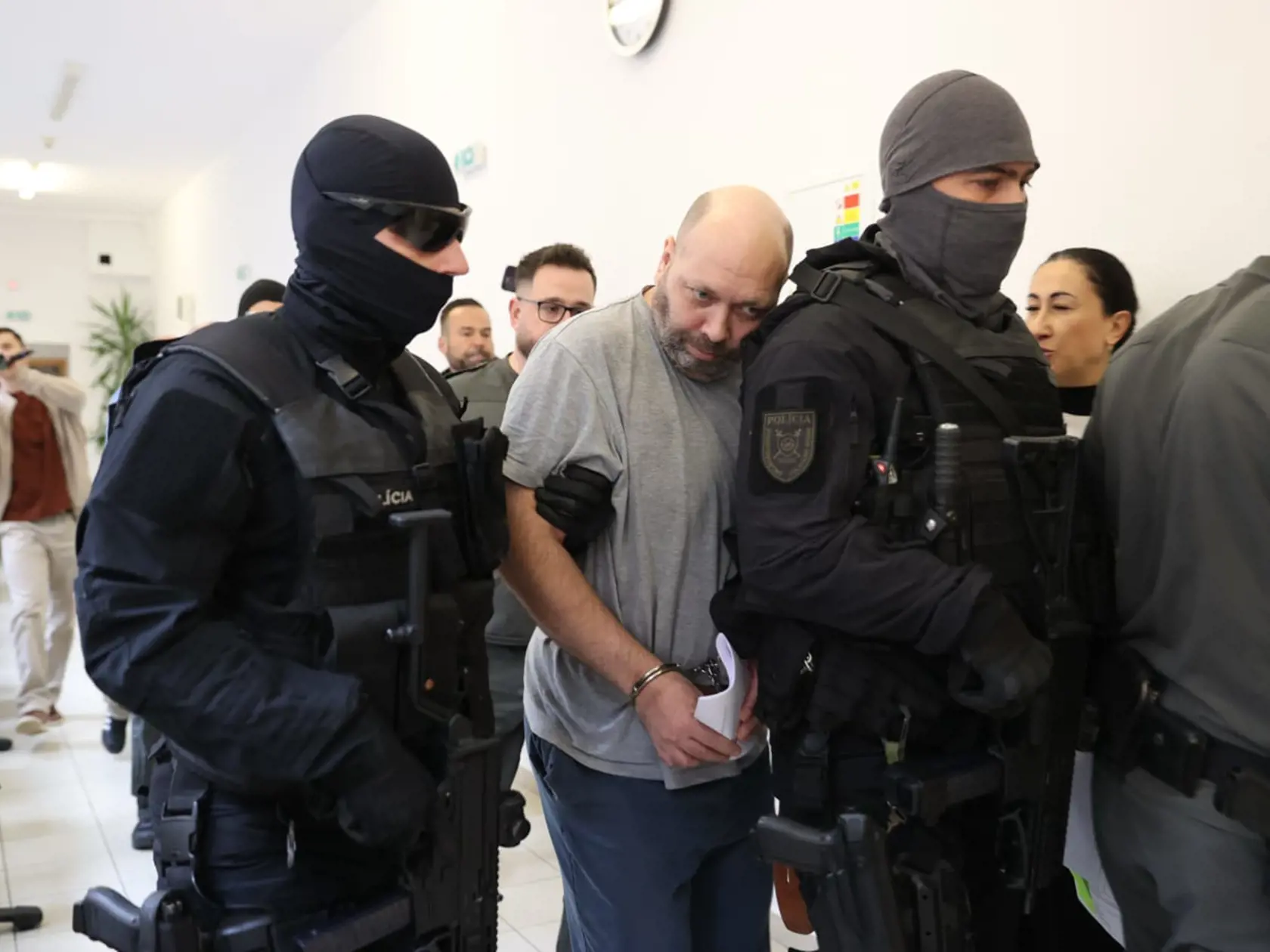 Tomáša (44), obvineného z vraždy svojich rodičov, privádzajú kukláči priviedli na súd 18. októbra 2024.