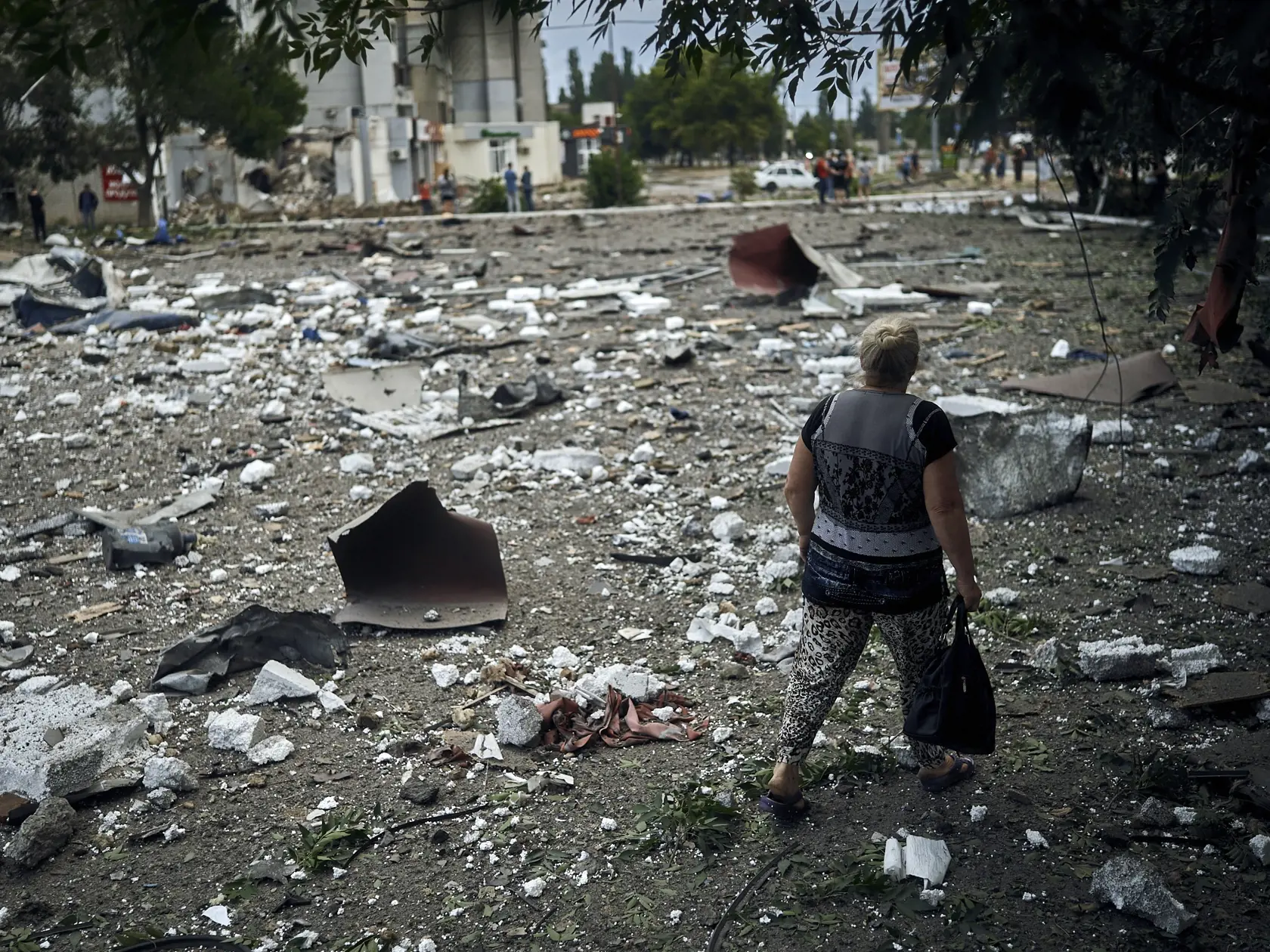 Žena kráča okolo budovy zničenej pri nočnom bombardovaní v Mykolajive na juhu Ukrajiny 3. augusta 2022.