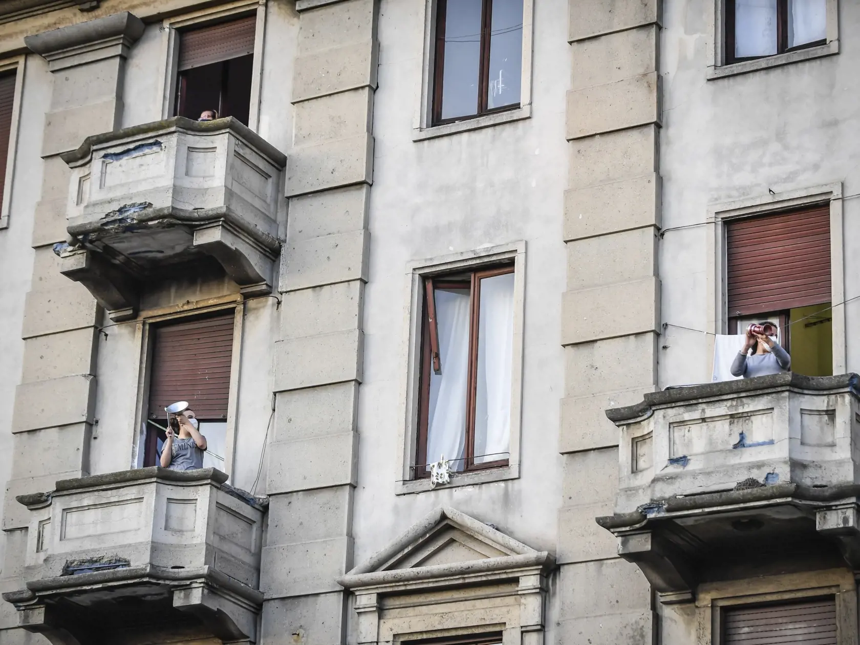 KK35 Miláno - Ľudia na svojich balkónoch hrajú a spievajú počas hromadnej akcie, ktorú spustili v Taliansku s cieľom spojiť ľudí a zvládnuť núdzový stav kvôli novému koronavírusu 13. marca 2020 v Miláne. FOTO TASR/AP
People lean out of their home's balconies to play and sing during a flash mob launched throughout Italy to bring people together and try to cope with the emergency of coronavirus, in Milan, Italy, Friday, March 13, 2020. Italians have been experiencing yet further virus-containment 