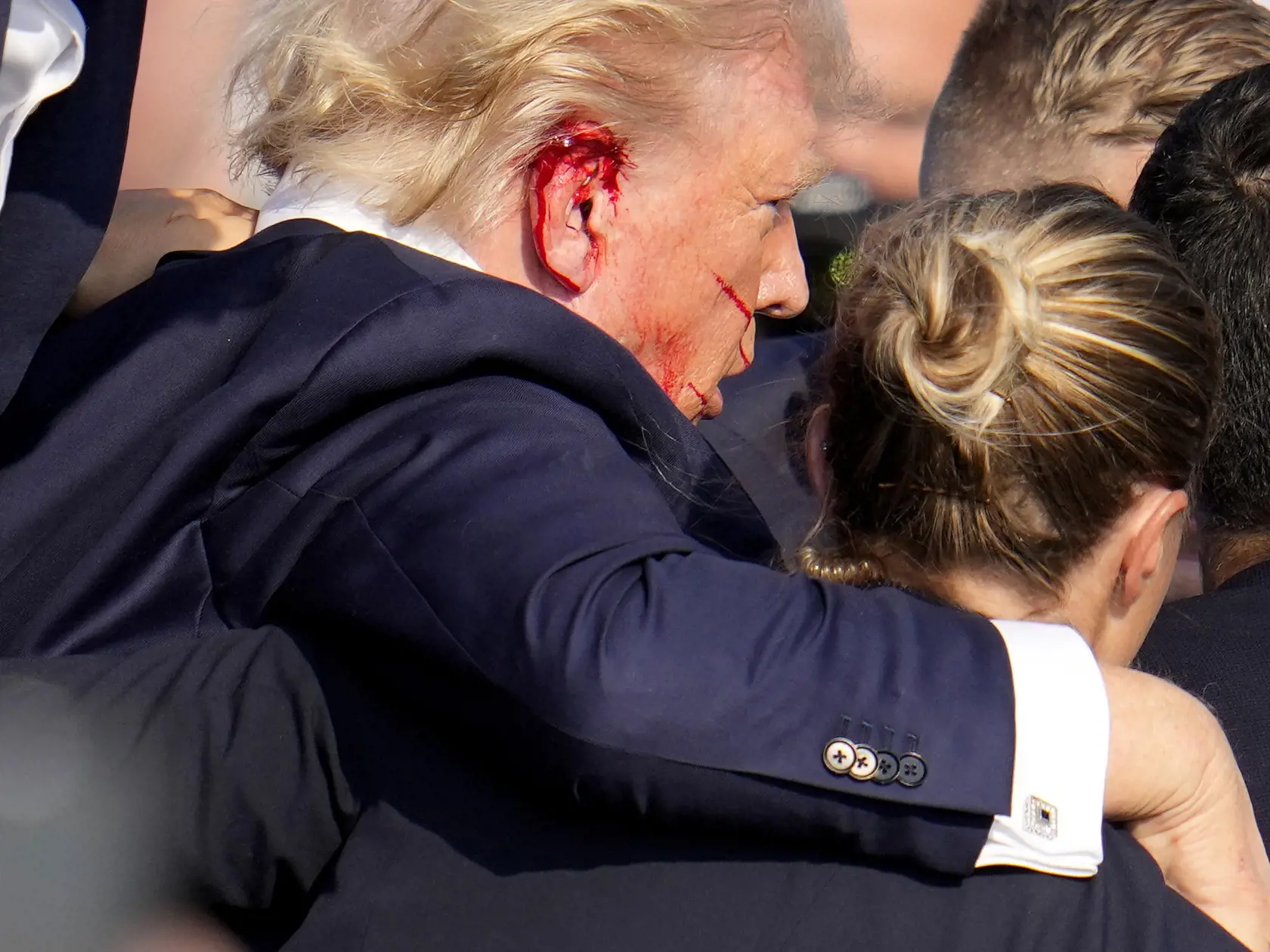 Republikánsky prezidentský kandidát Donald Trump odchádza za pomoci ochrankárov z predvolebného mítingu v meste Butler v americkom štáte Pensylvánia 13. júla 2024. Trump potvrdil, že v sobotu na mítingu v Pensylvánii ho zasiahla guľka. Tá mu prestrelila hornú časť pravého ucha. Bývalý americký prezident sa vyjadril na sociálnej sieti, informuje TASR.