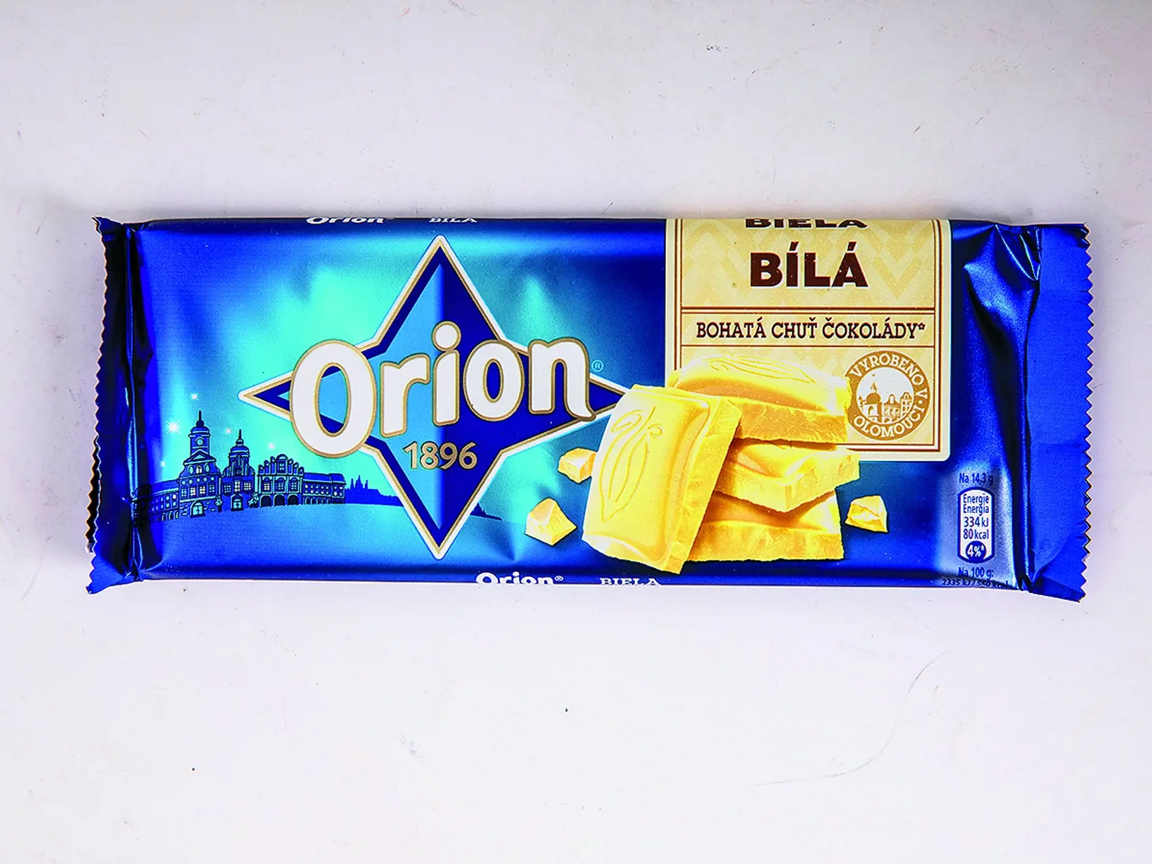 Biela
Orion, 100 g
Krajina pôvodu/ Česko
Zloženie/ cukor, sušené plnotučné mlieko, kakaové maslo, emulgátor: slnečnicový lecitín, vanilkový extrakt 
Energia v 100 g/ 2 335 kJ Tuky/ 34,3 g Sacharidy/ 54,5 g Bielkoviny/ 8,2 g
Redakcia hodnotí: Čokoláda má intenzívnu mliečnu vôňu, tvrdú konzistenciu a mierne drsnú textúru, dosť pomaly sa rozpúšťa na jazyku. Chuť je veľmi dobrá, ale pocitovo príliš sladká, s mierne kyslastým akcentom a dochuťou po orechoch. Z porovnávaných čokolád má druhý najn