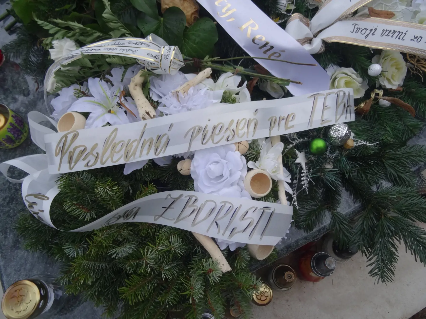 "Posledná pieseň pre Teba, lúčia sa ZBORISTI" znie nápis na jednom z vencov so zvláštnymi  doplnkami medzi bielymi látkovými kvetmi. (archívne foto)
