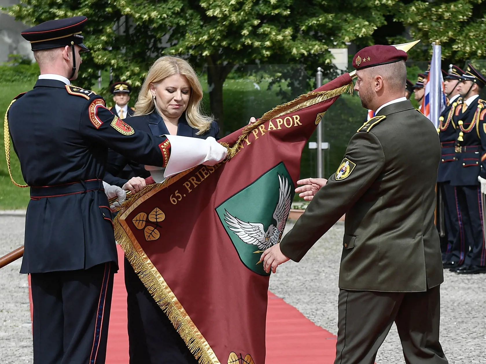 Na snímke uprostred prezidentka SR Zuzana Čaputová odovzdáva bojovú zástavu do rúk veliteľovi 65. prieskumného práporu Prešov podplukovníkovi Mariánovi Brinčekovi (vpravo) na nádvorí Prezidentského paláca 23. mája 2024 v Bratislave. FOTO TASR - Pavel Neubauer