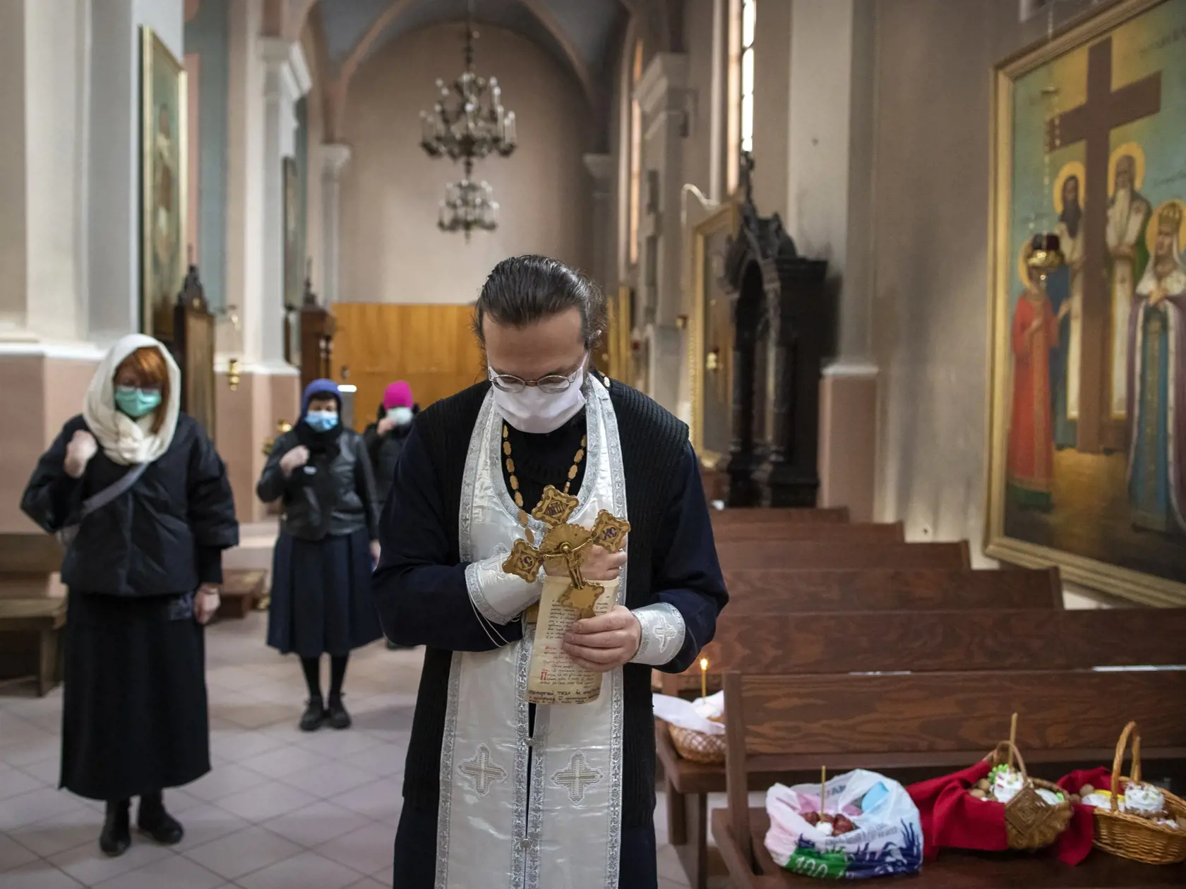 JB 32 Vilnius - Litovský pravoslávny kňaz a veriaci s ochrannými rúškami na zabránenie šíreniu nového koronavírusu sa modlia počas veľkonočnej pravoslávnej bohoslužby posvätenia jedál v pravoslávnom kostole vo Vilniuse 18. apríla 2020. Pravoslávni veriaci oslavujú Veľkonočné sviatky. FOTO TASR/AP