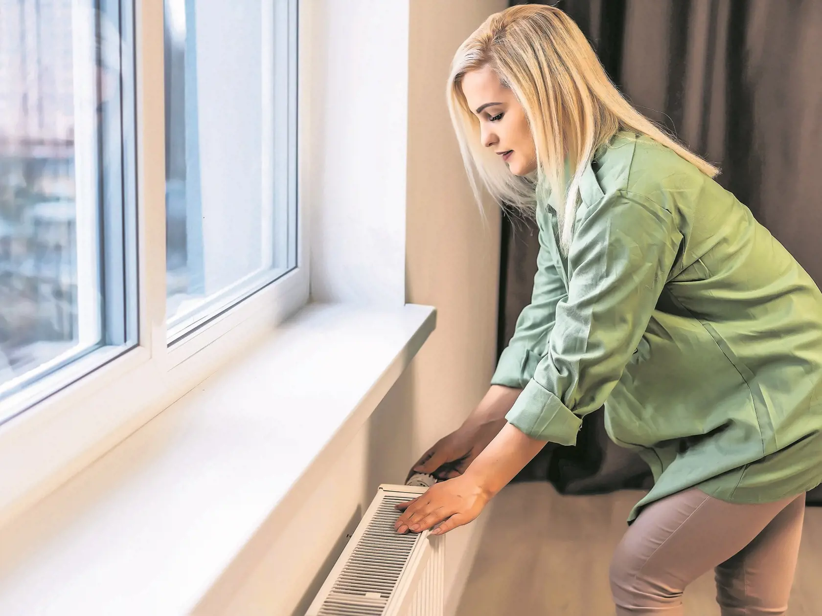 Young,And,Beautiful,Blond,Woman,Touching,The,Radiator.,Heating,Season