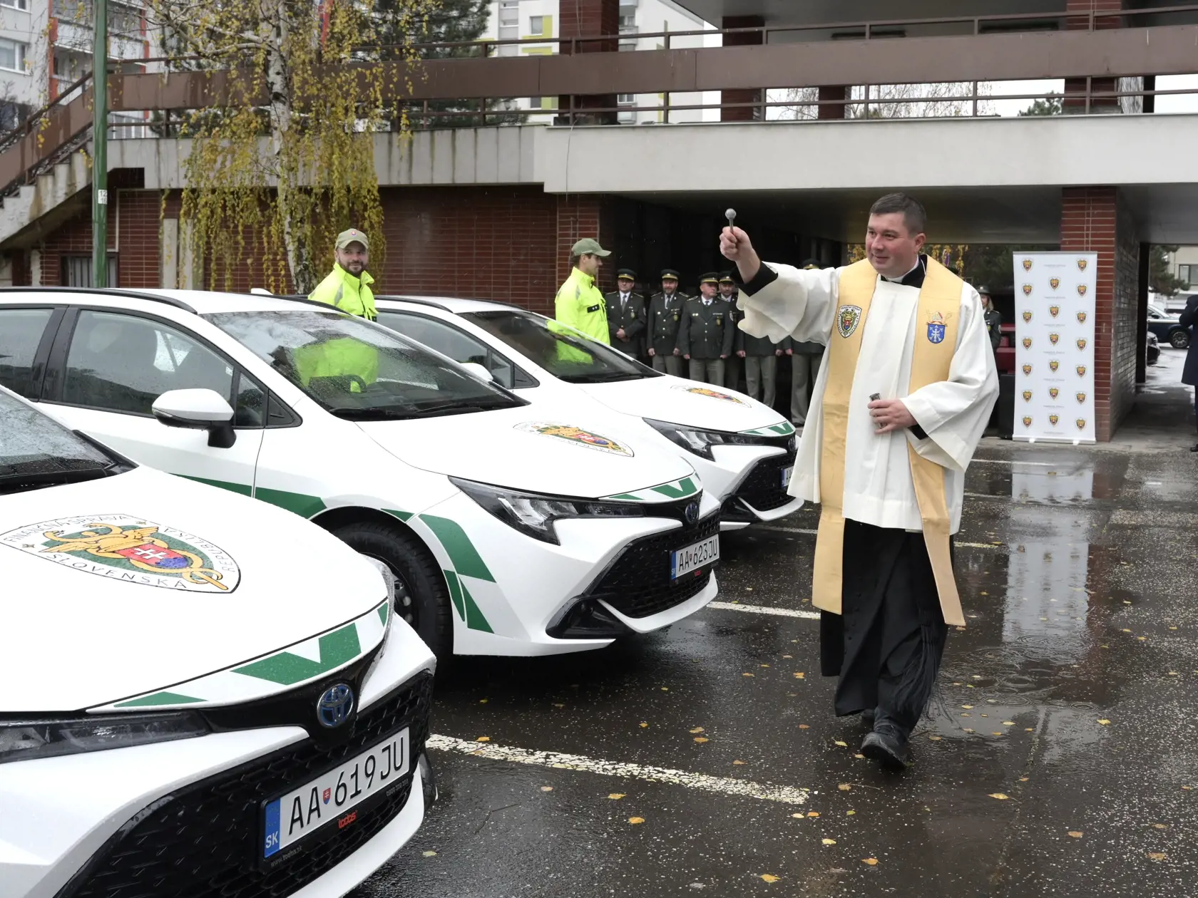 Kňaz požehnáva prvú várku nových motorových vozidiel pre colné úrady, ktorú slávnostne odovzdal prezident Finančnej správy (FS)  SR Jozef Kiss (vpravo)  v Bratislave vo štvrtok 21. decembra 2023. Šéf finančnej správy odovzdal vo štvrtok 16 z celkového počtu 91 služobných motorových vozidiel. FOTO TASR - Pavel Neubauer