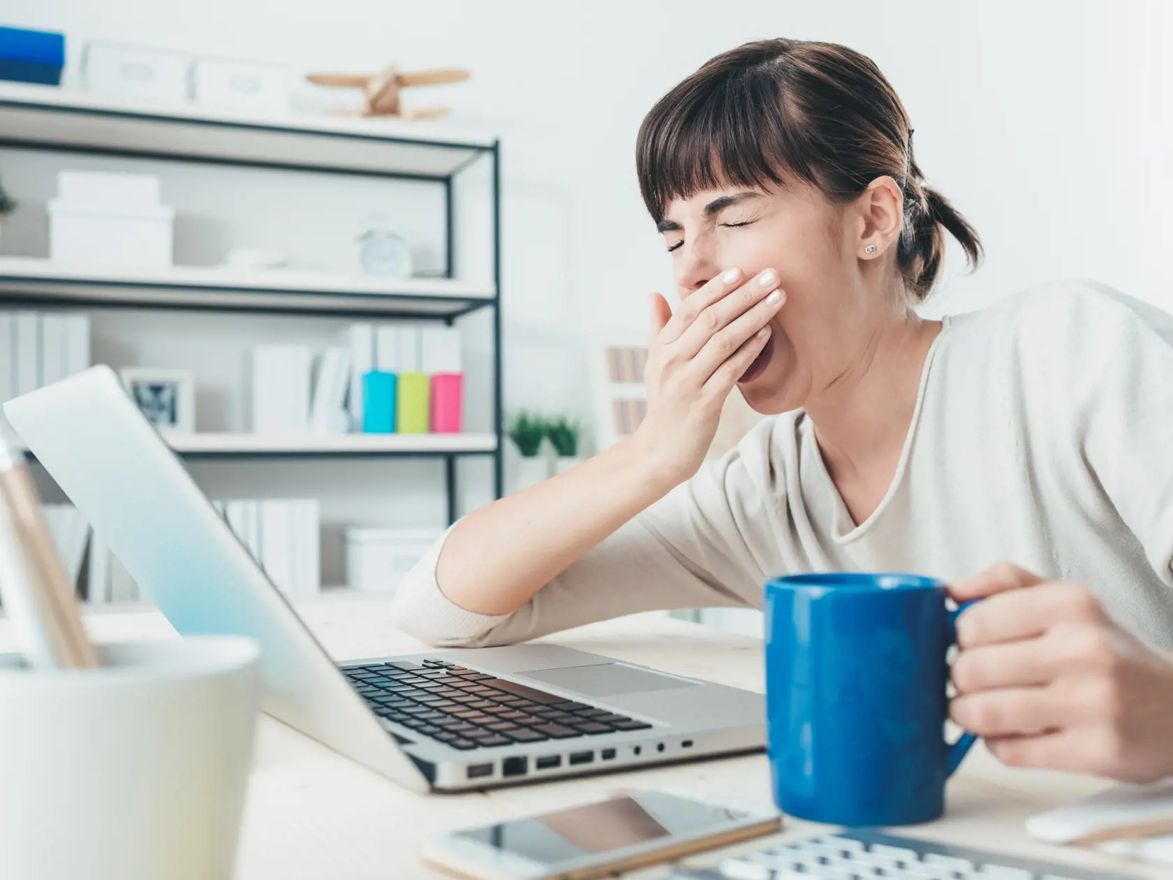 Tired,Sleepy,Woman,Yawning,,Working,At,Office,Desk,And,Holding