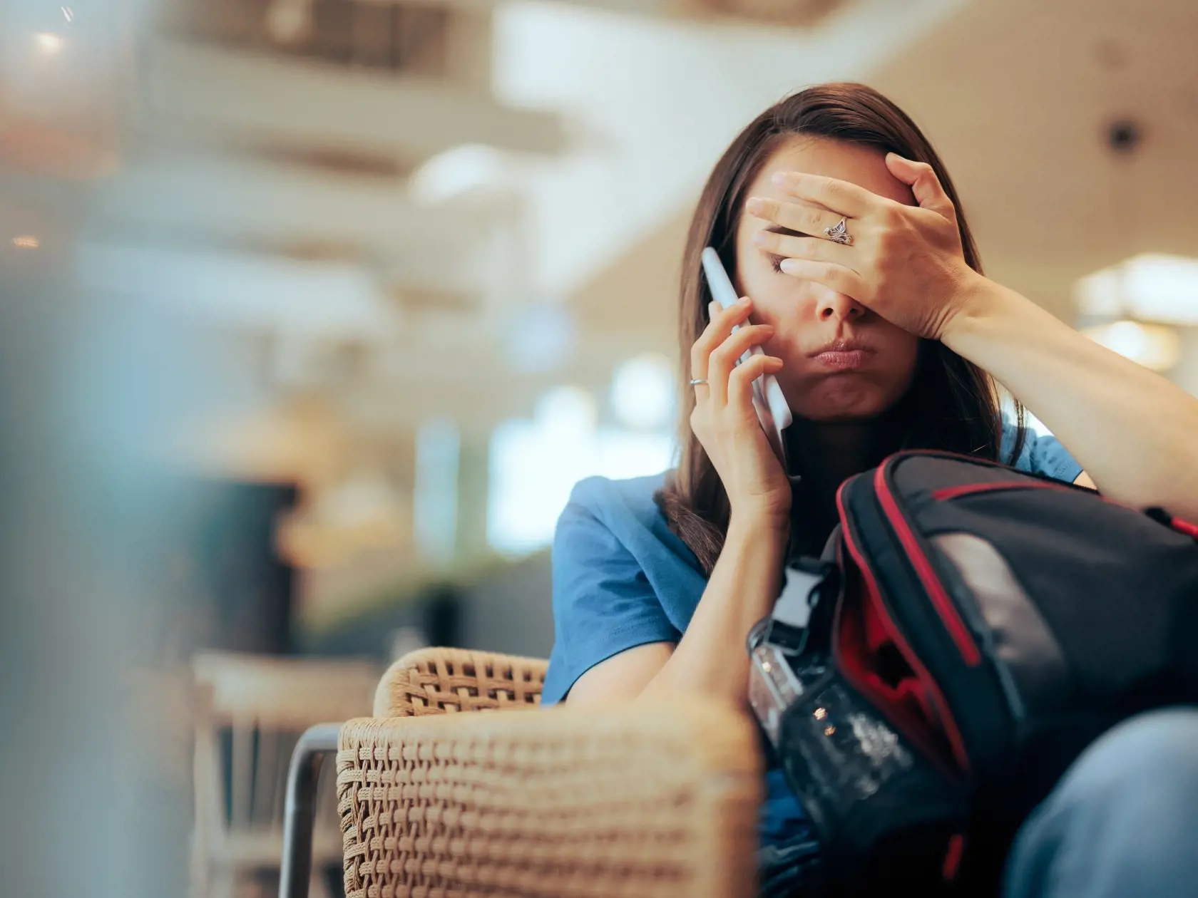 Unhappy,Woman,Talking,On,The,Phone,Waiting,In,An,Airport