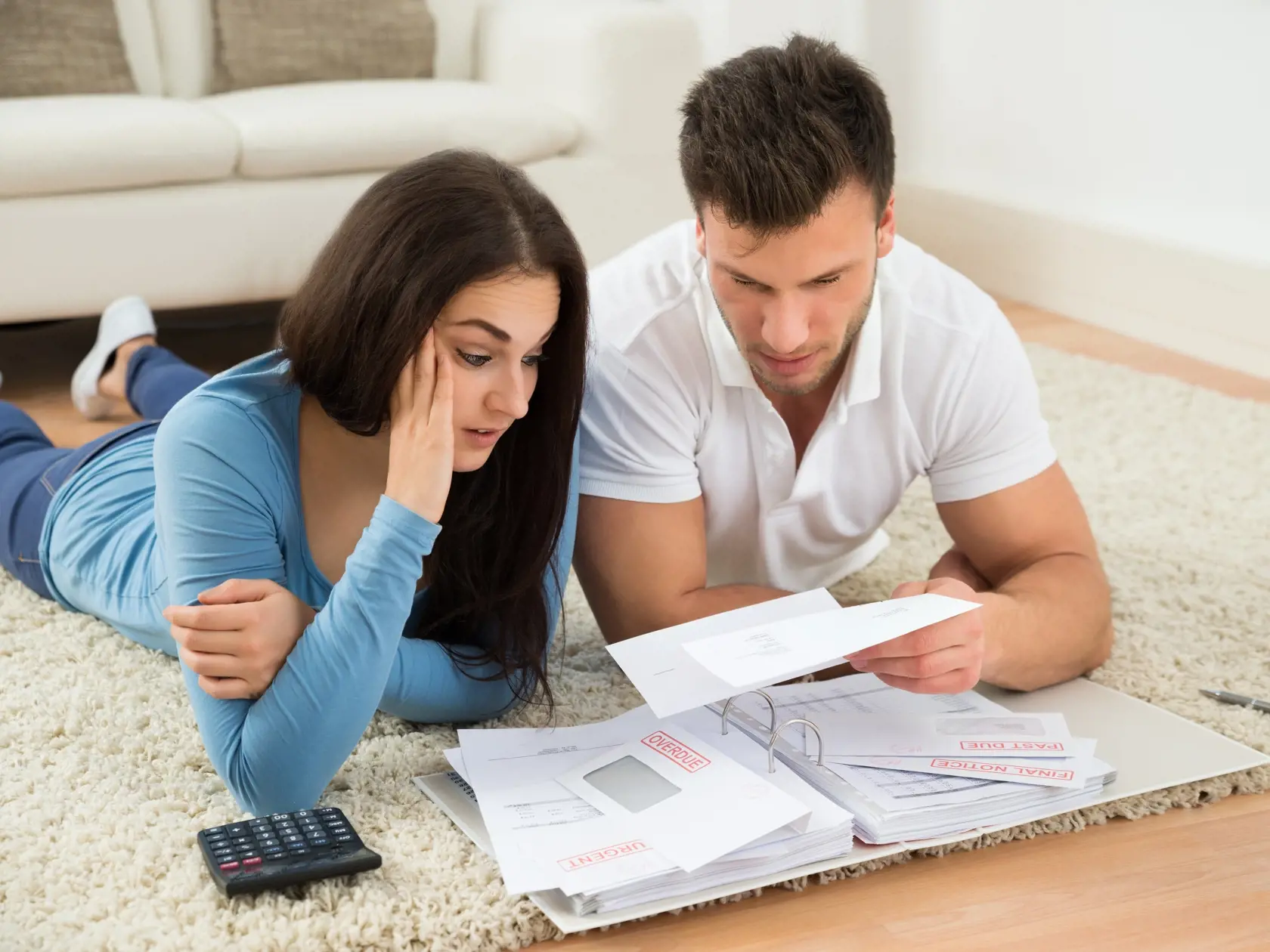 Worried,Young,Couple,Lying,On,Carpet,Calculating,Their,Bills,At