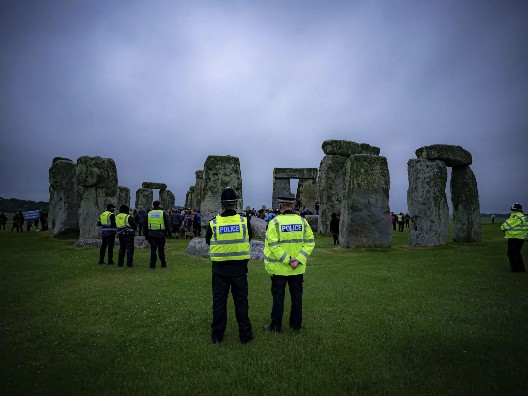 KK22 Salisbury - Policajti kontrolujú ľudi, ktorí preskočili plot, a čakajú na východ slnka vo vnútri zatvoreného Stonehengu počas osláv letného slnovratu 21. júna 2021 neďaleko Salisbury. FOTO TASR/AP
Police keep watch as people stand inside the stone circle during Summer Solstice at Stonehenge, where some people jumped over the fence to enter the stone-circle to watch the sun rise at dawn of the longest day of the year in the UK, in Amesbury, England, Monday June 21, 2021. The prehistoric monu