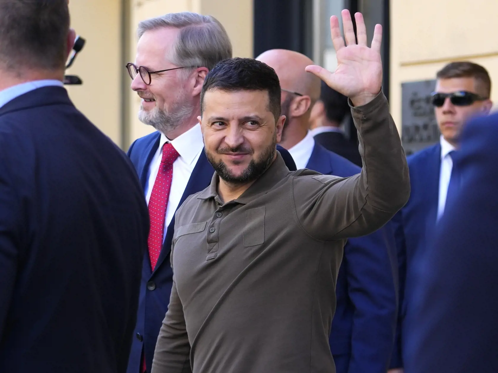 Ukrajinský prezident Volodymyr Zelenskyj máva po kladení kvetov k pamätnej doske 17. novembra na Národnej triede, v pozadi uprostred český premiér Petr Fiala 7. júla 2023 v Prahe.