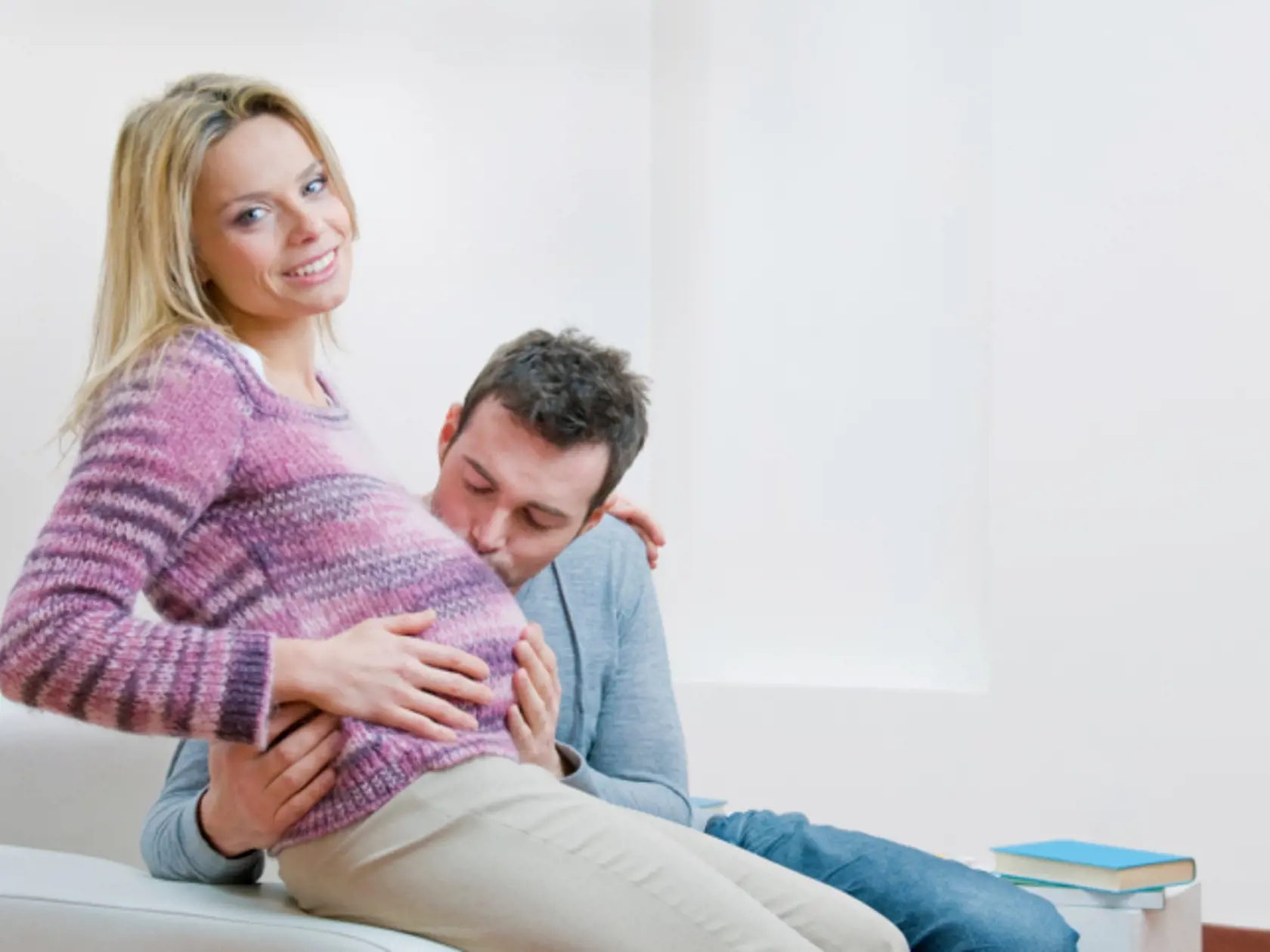 Happy father give a sweet kiss to the mother's bump of their new child